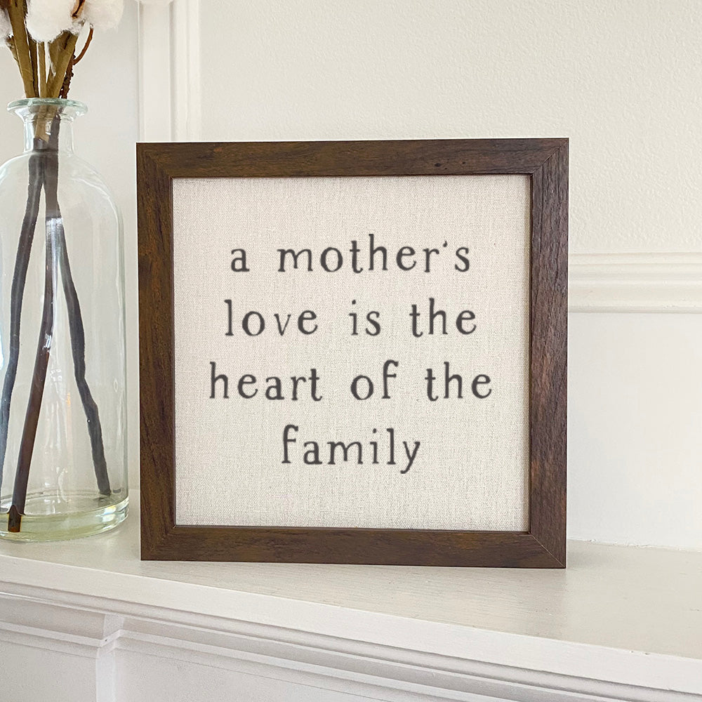 Framed sign reading 'Mother's Love is the heart' with a natural linen background and wooden frame options.