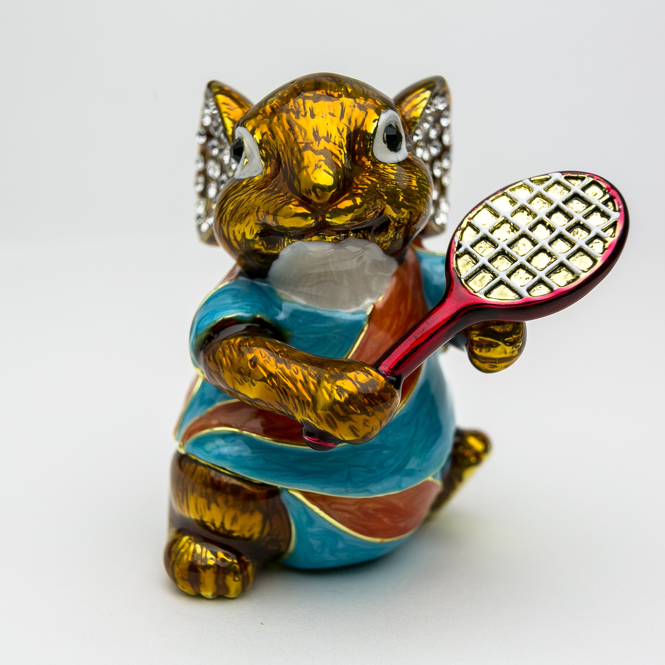 A beautifully crafted enamel trinket box featuring a mouse playing tennis, adorned with Austrian crystals and plated with 24K gold.