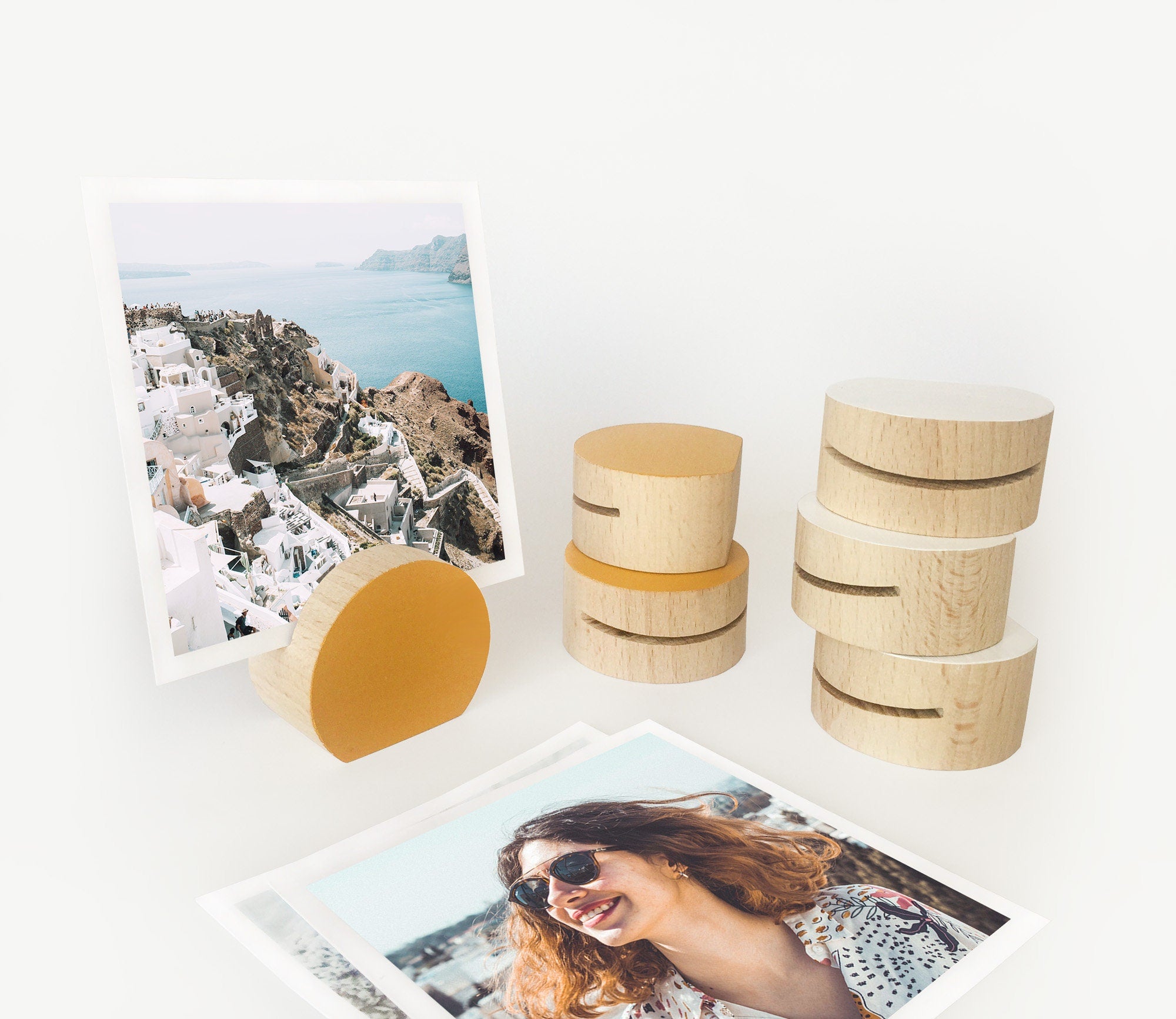 A handcrafted mustard moon shaped card holder made from eco-friendly wood, displaying small art prints and photos.