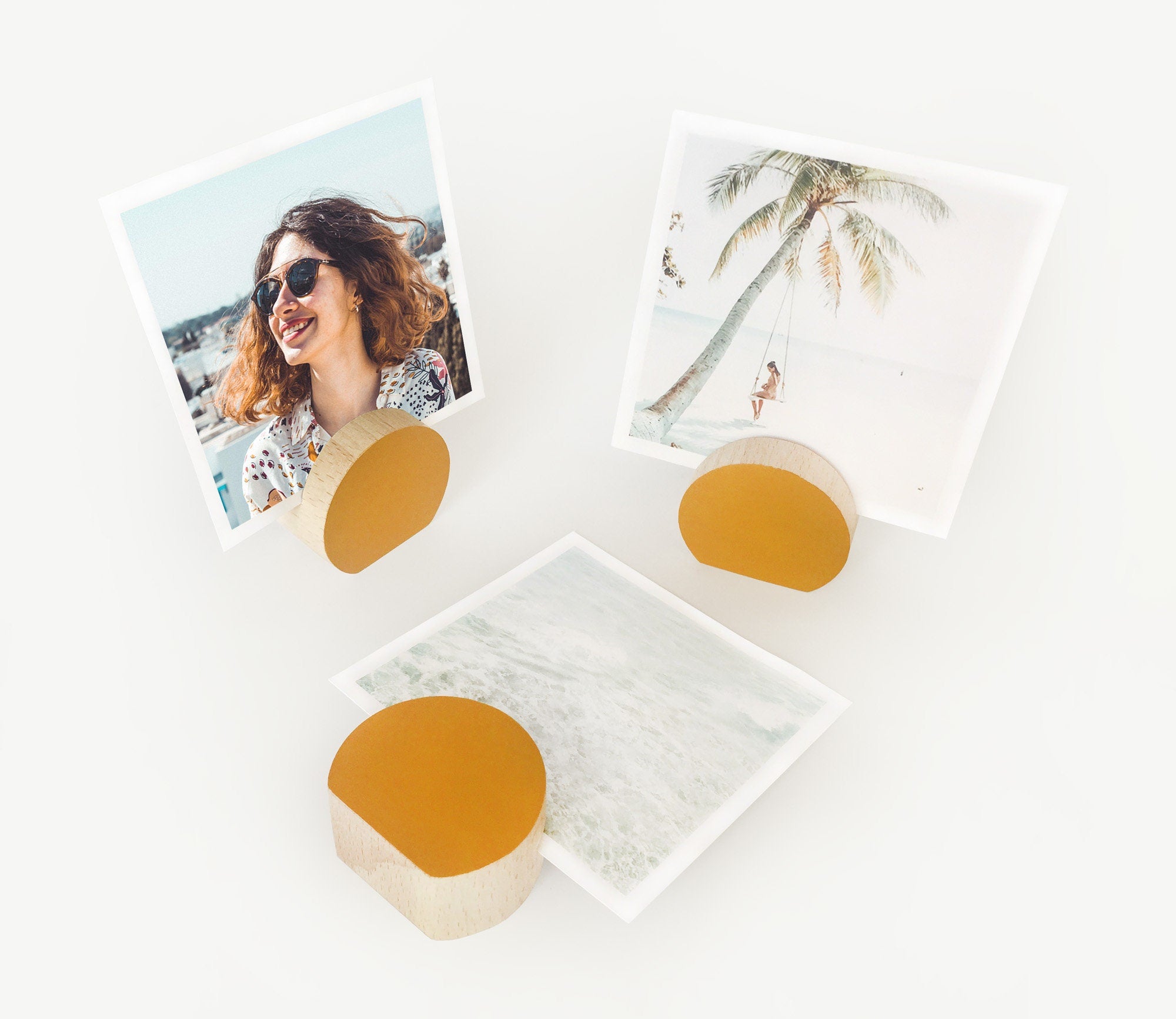 A handcrafted mustard moon shaped card holder made from eco-friendly wood, displaying small art prints and photos.