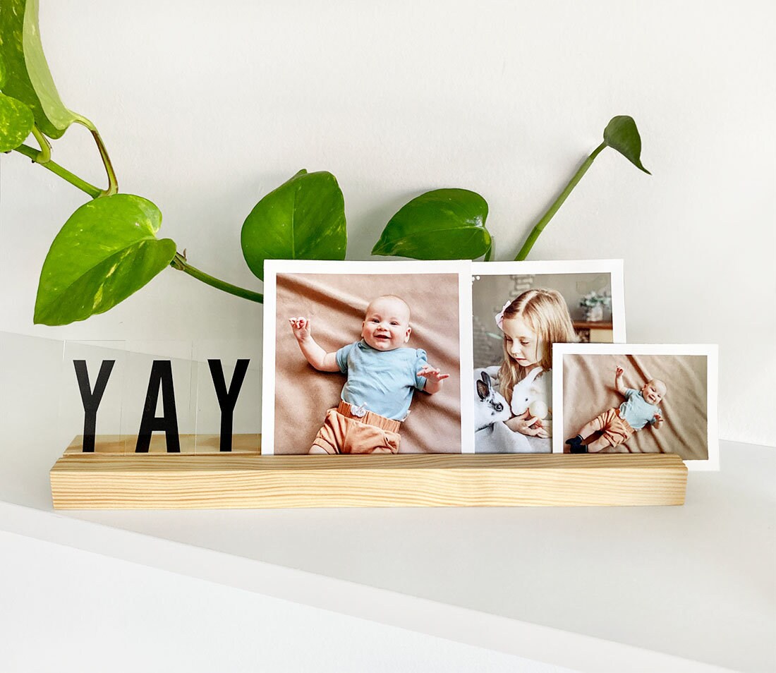 Natural wooden photo ledge displaying various photos and art prints, showcasing its elegant design and eco-friendly material.