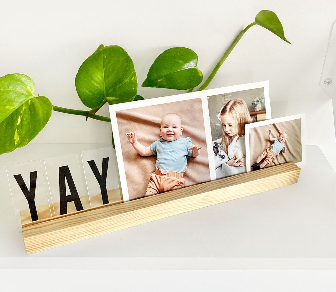 Natural wooden photo ledge displaying various photos and art prints, showcasing its elegant design and eco-friendly material.