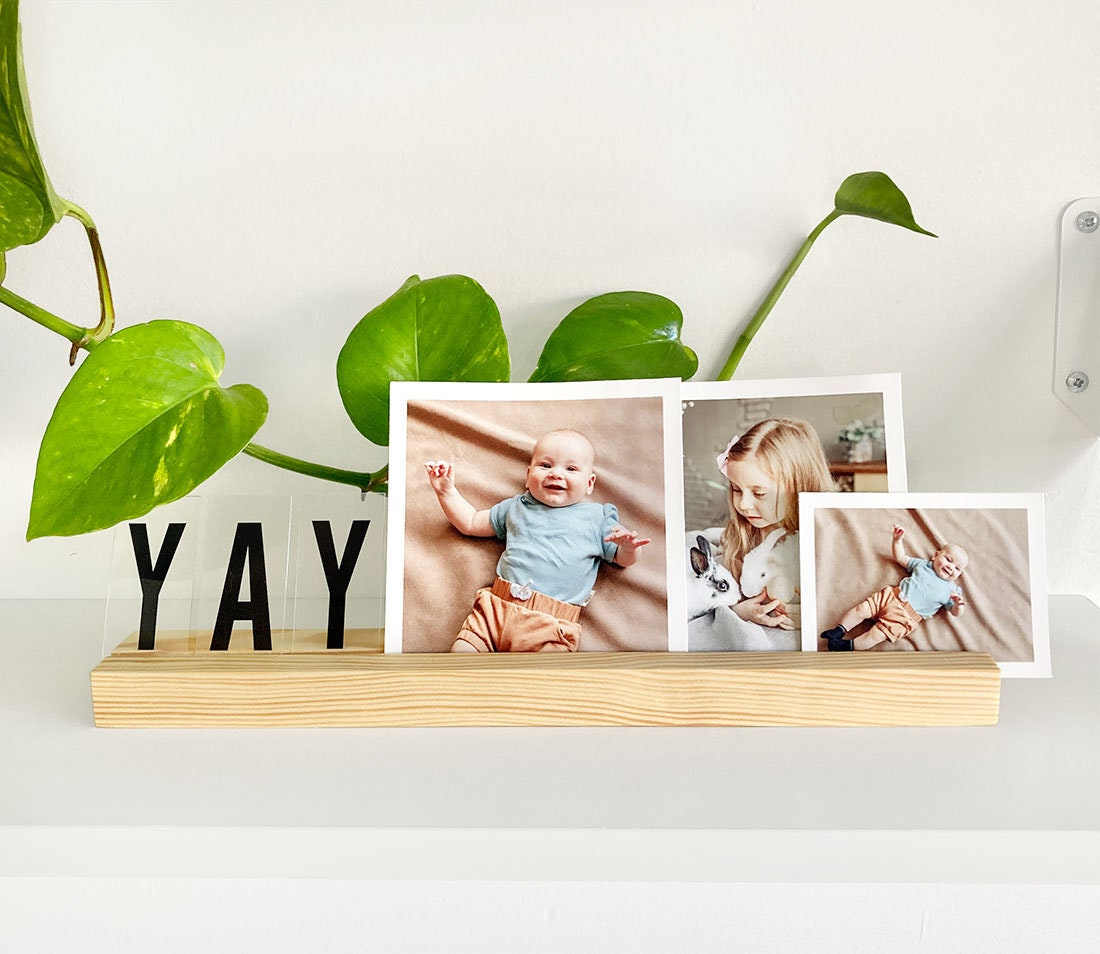 Natural wooden photo ledge displaying various photos and art prints, showcasing its elegant design and eco-friendly material.