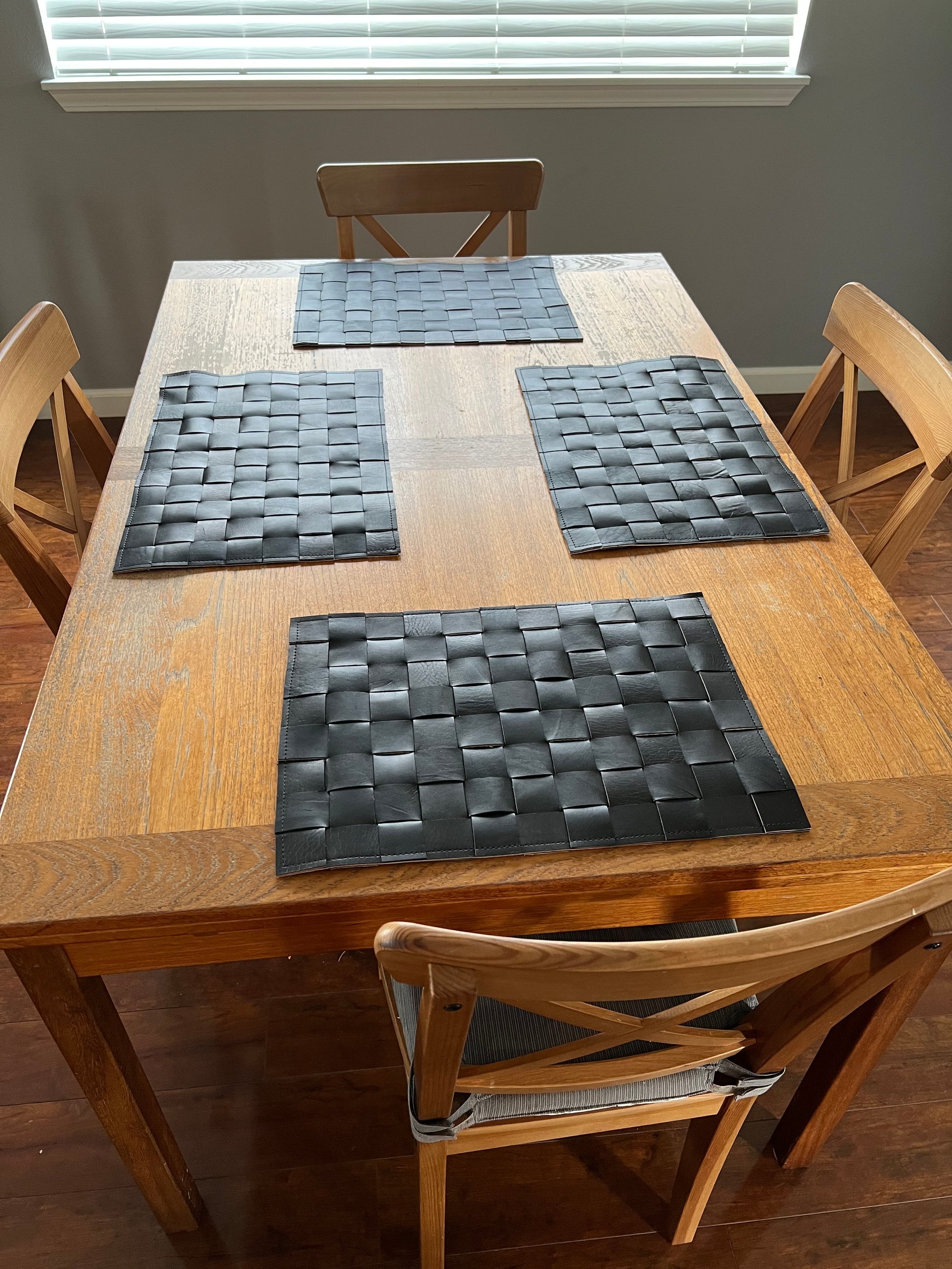 A set of four handmade leather placemats made from premium cowhide, showcasing a rustic and elegant design.