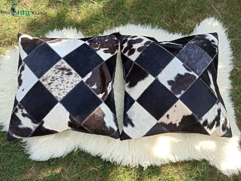 Pack of two genuine cow skin leather pillow covers with unique tricolor patterns in black, brown, and white, showcasing a luxurious texture.