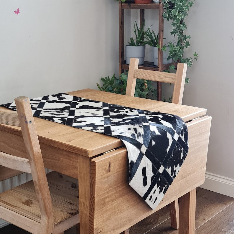 Pack of two handmade cowhide table runners, 16" x 60", showcasing unique patterns and colors.