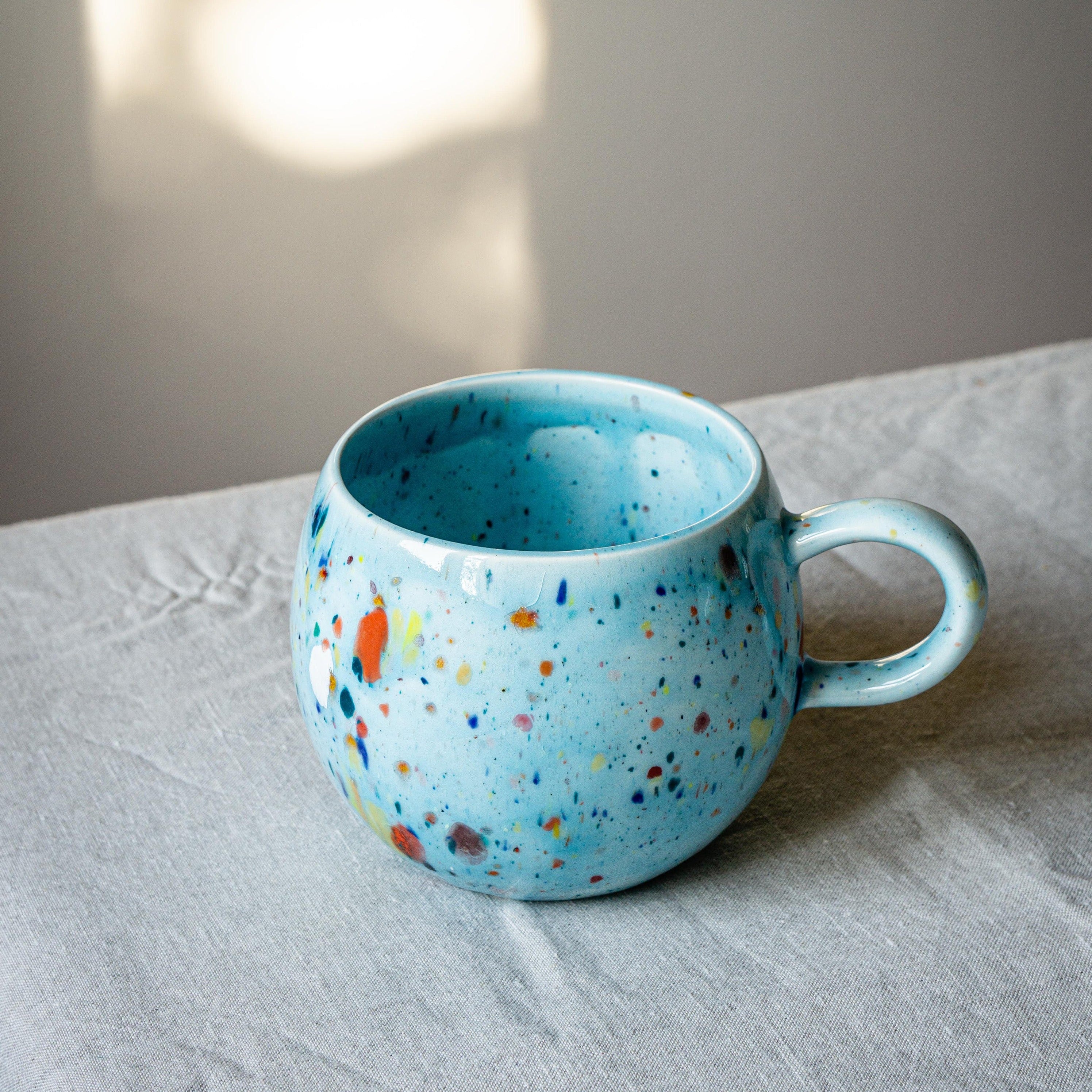 A vibrant blue ceramic Party Ball Mug with a shiny glaze finish, showcasing its unique handmade imperfections and elegant design.