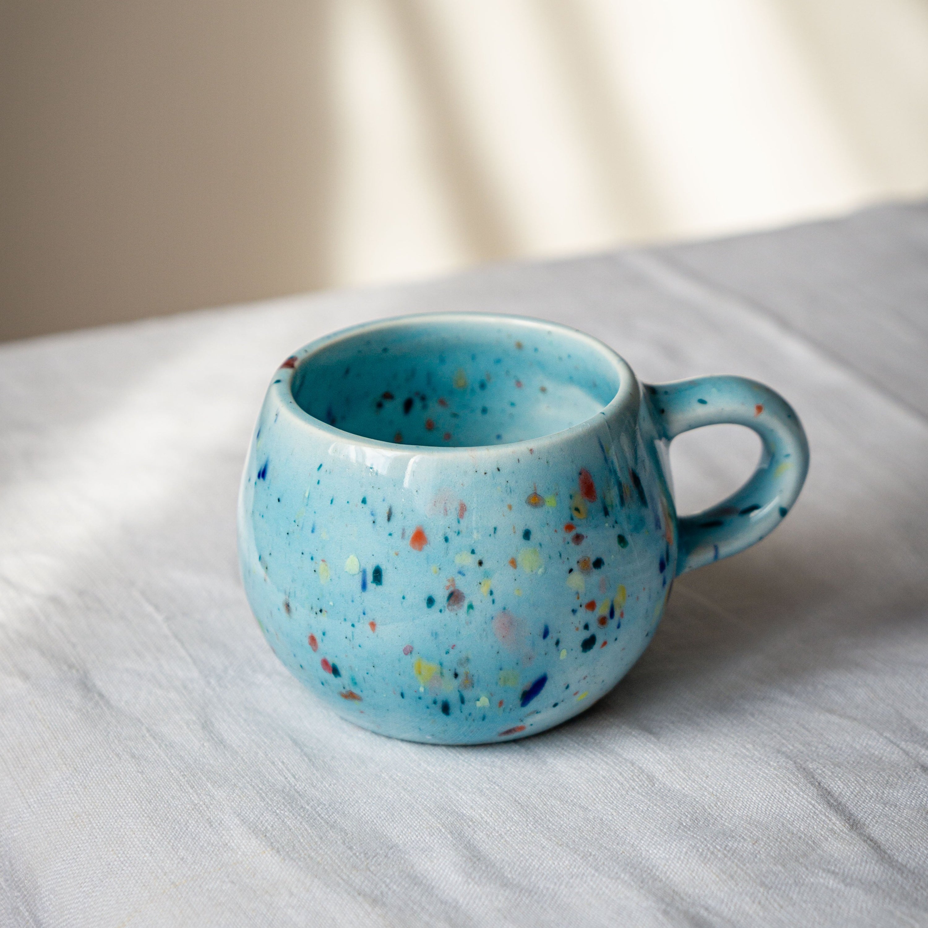 A vibrant blue ceramic Party Ball Mug with a shiny glaze finish, showcasing its unique handmade imperfections and elegant design.