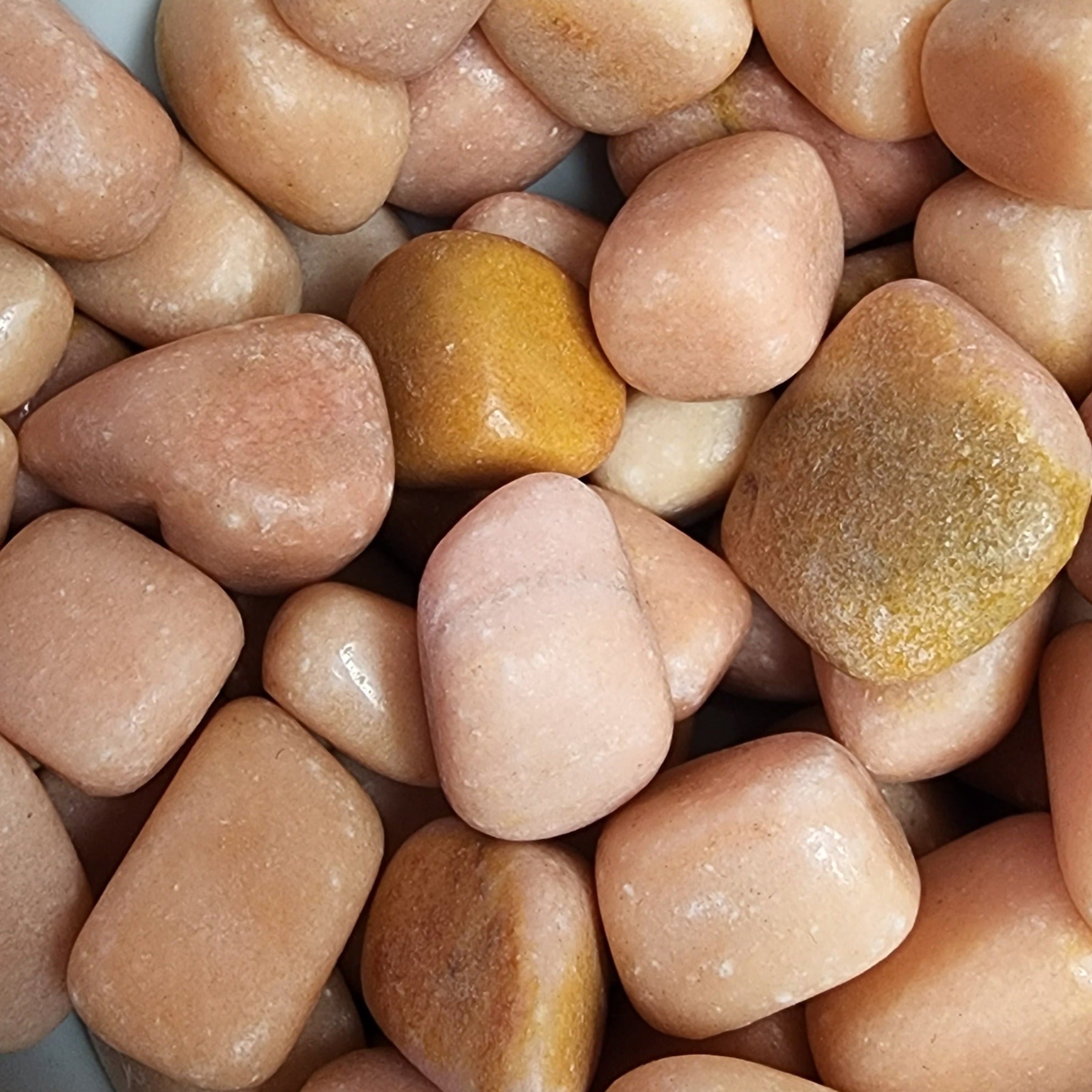 A collection of smooth, peach-colored tumbled stones, showcasing their natural beauty and unique shapes.