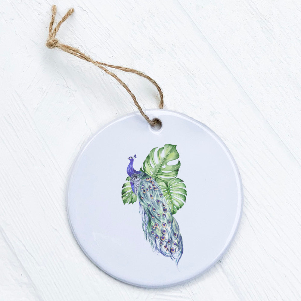 A beautifully crafted porcelain ornament featuring a peacock and monstera leaves design, showcasing vibrant colors and a glossy finish.