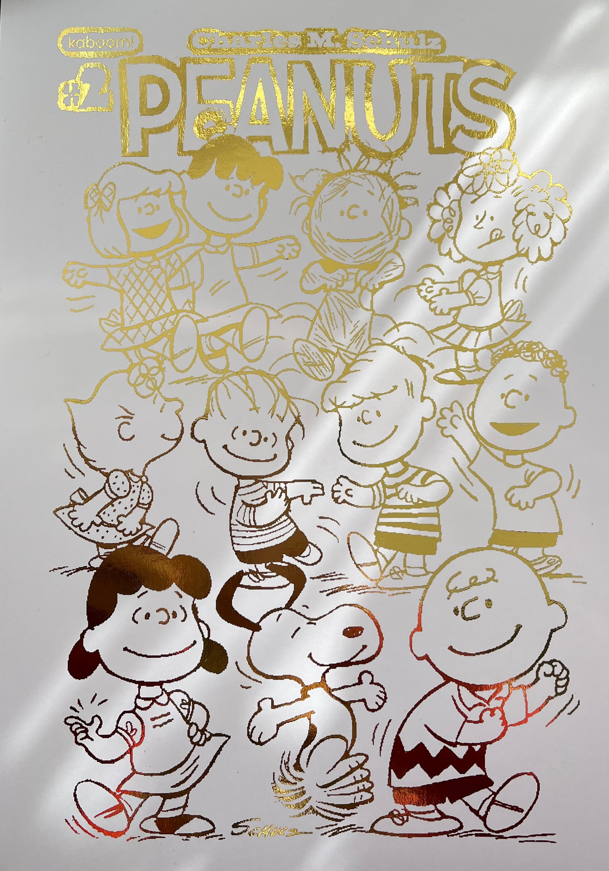 Peanuts Comic Cover & Comic Strip Foil Print featuring Charlie Brown, Snoopy, and other iconic characters in gold foil accents.