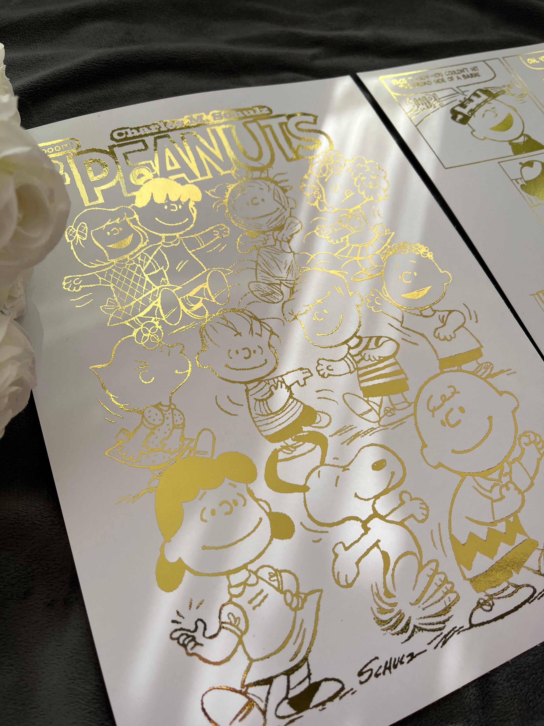 Peanuts Comic Cover & Comic Strip Foil Print featuring Charlie Brown, Snoopy, and other iconic characters in gold foil accents.