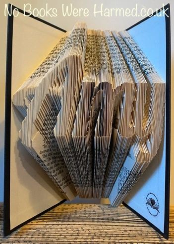 Hand-folded book art displaying custom words and punctuation, showcasing unique designs from vintage books.