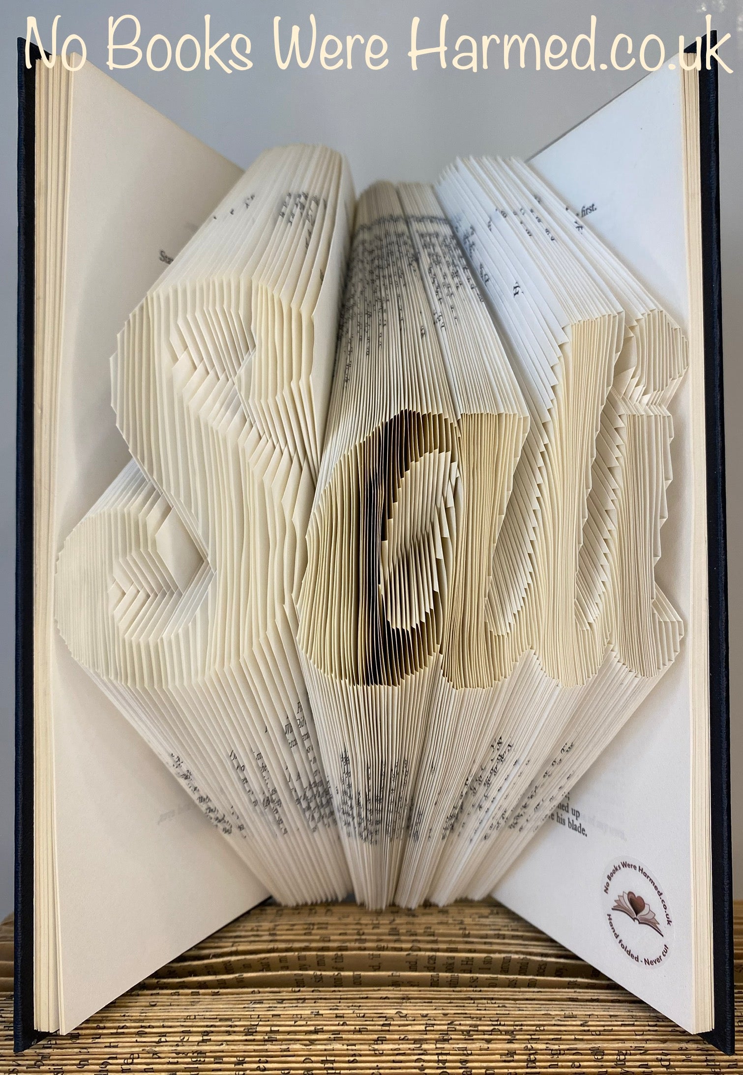 Hand-folded book art displaying custom words and punctuation, showcasing unique designs from vintage books.