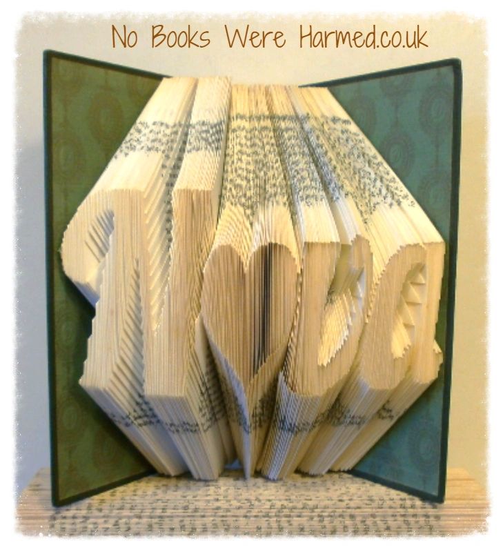 Hand-folded book art displaying custom words and punctuation, showcasing unique designs from vintage books.