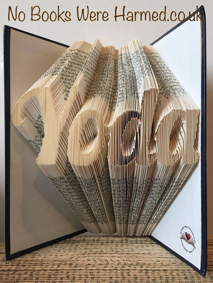 Hand-folded book art displaying custom words and punctuation, showcasing unique designs from vintage books.