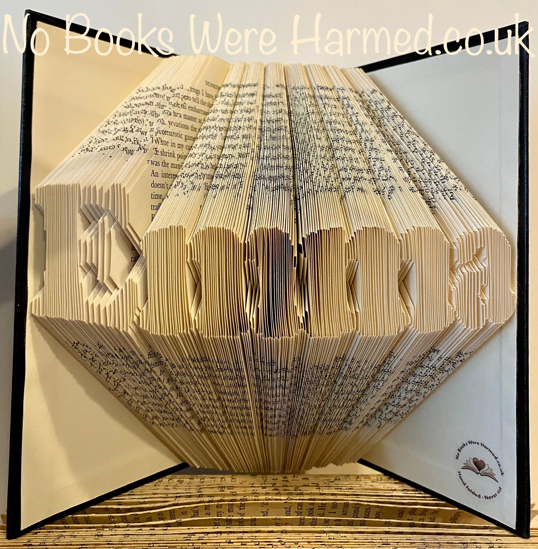 Custom book art featuring hand-folded letters from vintage books, showcasing unique designs and colors.