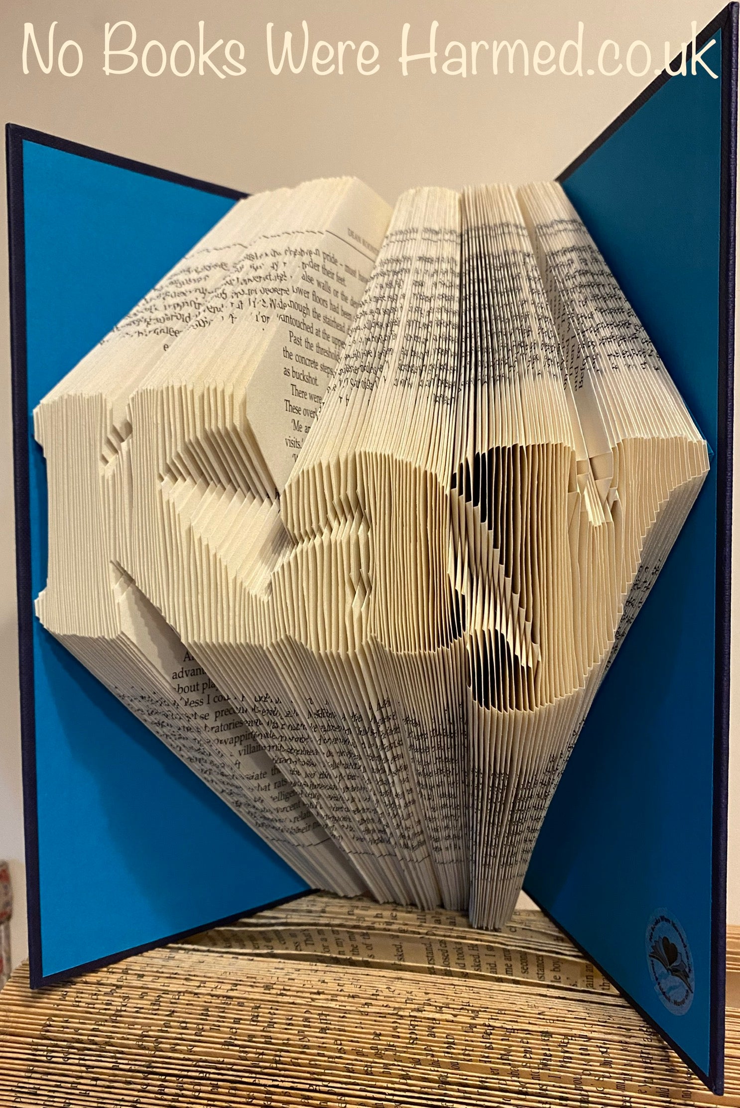 Custom book art featuring hand-folded letters from vintage books, showcasing unique designs and colors.