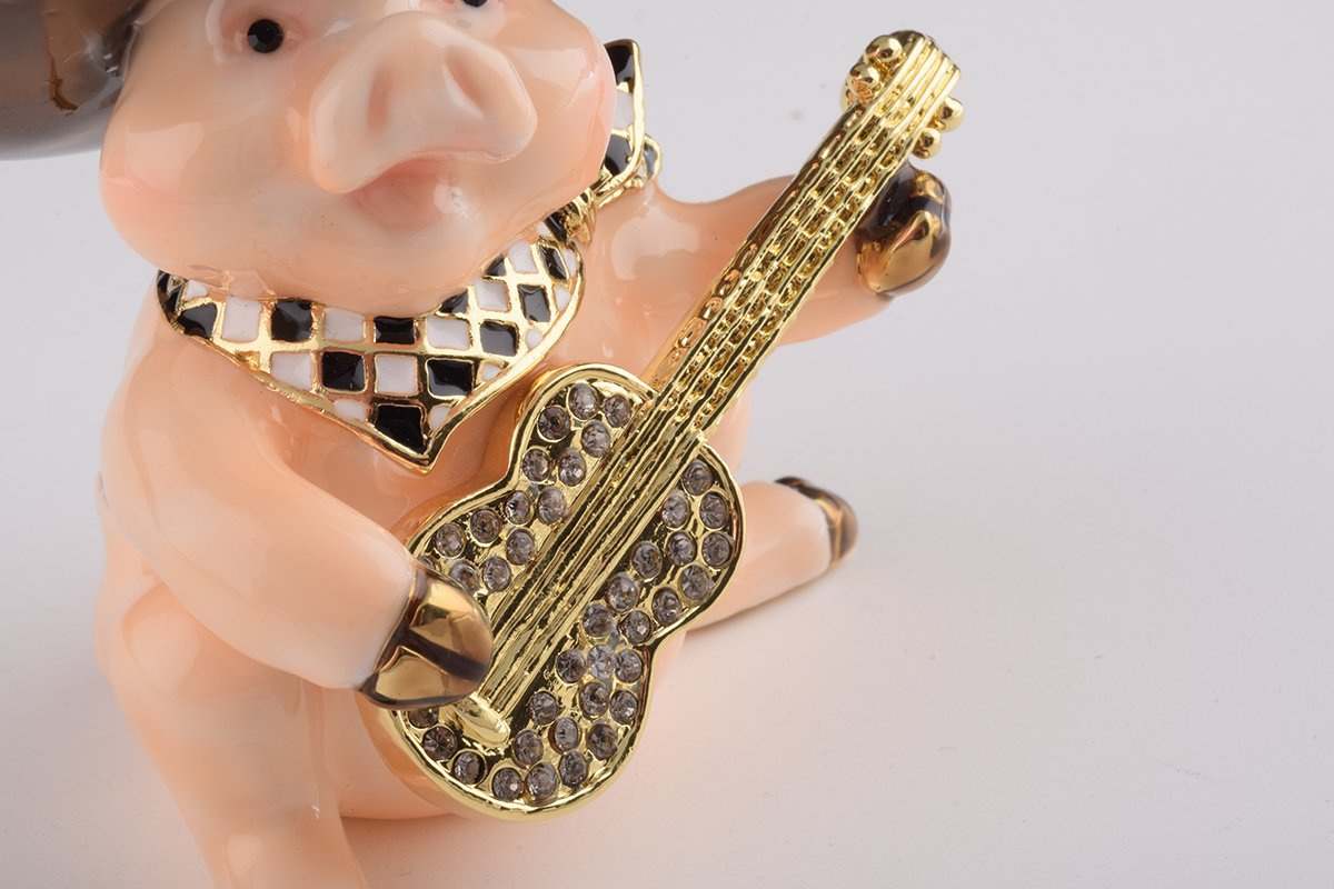 A charming enamel painted trinket box shaped like a pig playing guitar, adorned with Austrian crystals and gold plating.