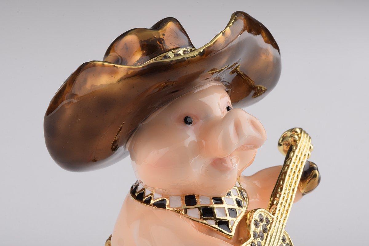 A charming enamel painted trinket box shaped like a pig playing guitar, adorned with Austrian crystals and gold plating.