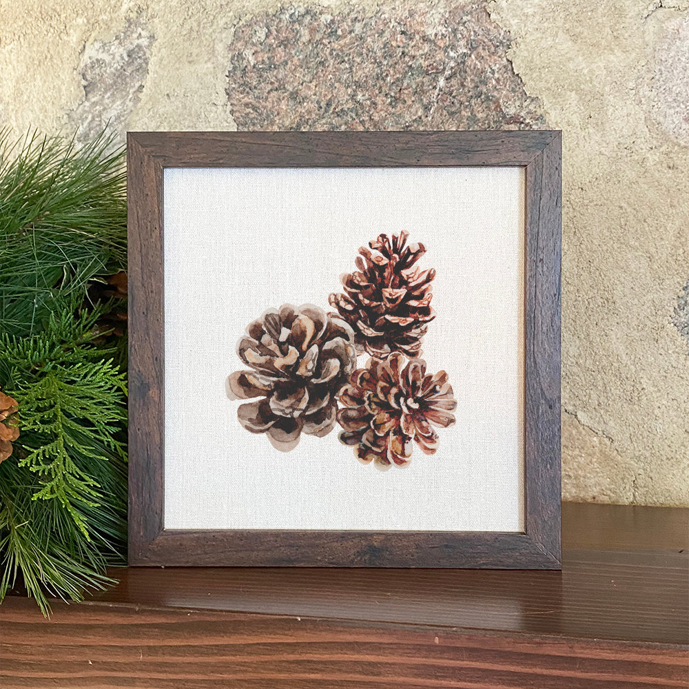 A beautifully framed Pinecones sign with a natural wood frame, featuring eco-friendly printing on a linen-look background.