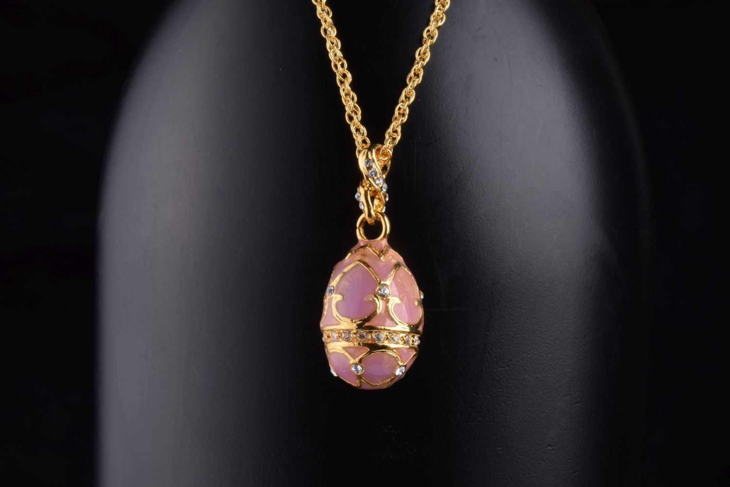 A beautiful pink egg pendant necklace adorned with Austrian crystals, showcasing intricate hand-painted enamel details and 24K gold plating.