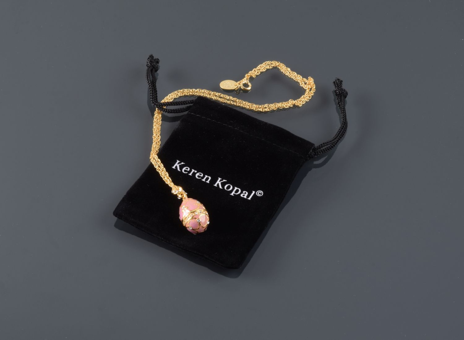 A beautiful pink egg pendant necklace adorned with Austrian crystals, showcasing intricate hand-painted enamel details and 24K gold plating.