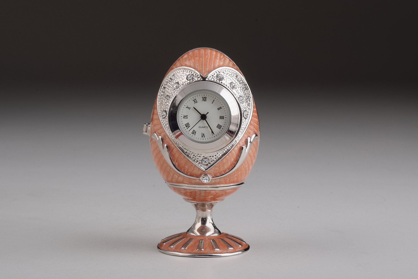 A stunning pink Faberge egg trinket box with clock, adorned with sparkling Austrian crystals and featuring a luxurious gold or silver plating.