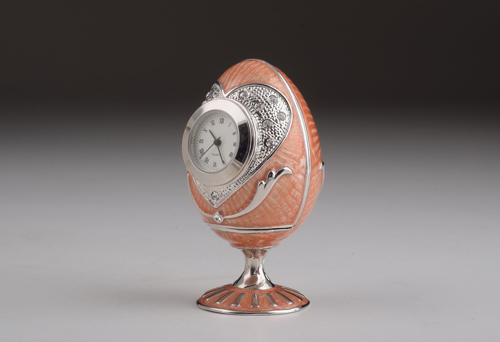 A stunning pink Faberge egg trinket box with clock, adorned with sparkling Austrian crystals and featuring a luxurious gold or silver plating.