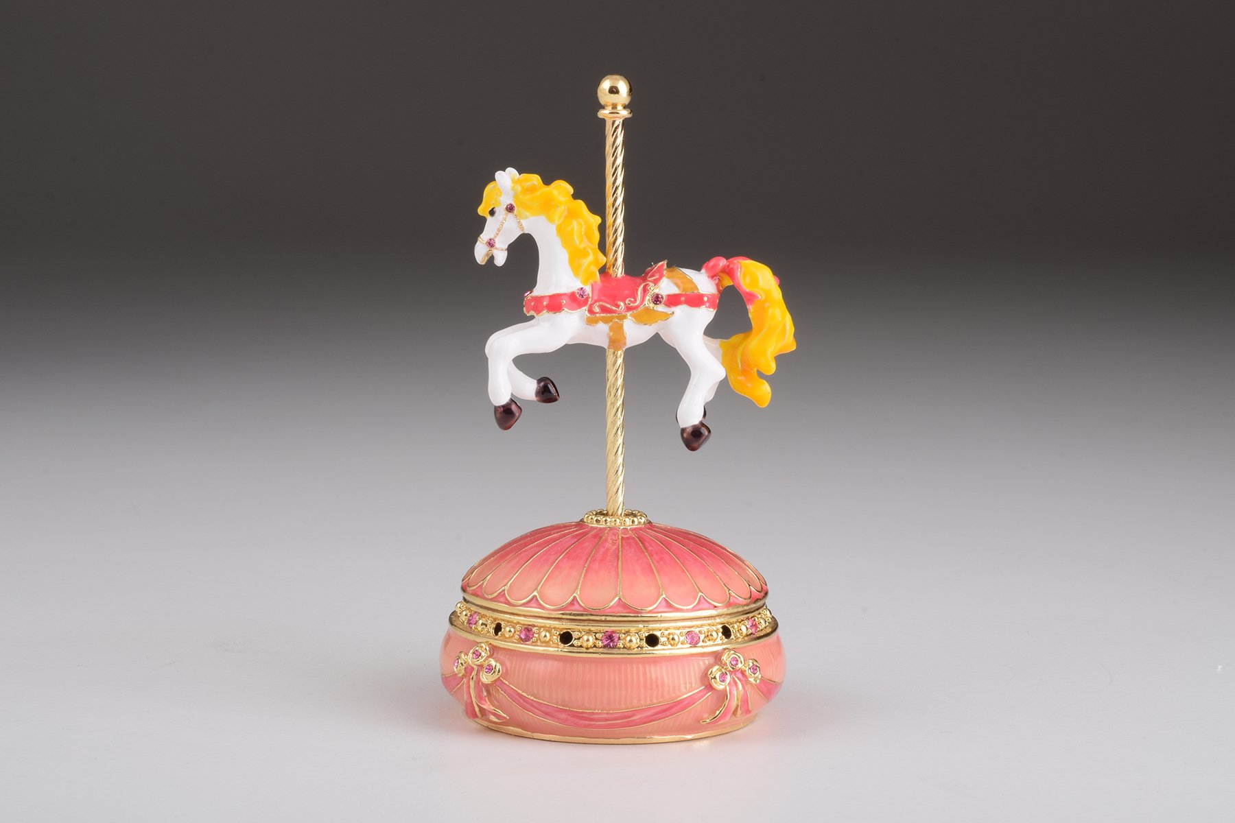 A beautifully crafted Pink Wind up Musical Carousel trinket box adorned with sparkling Austrian crystals and plated in 24K gold.