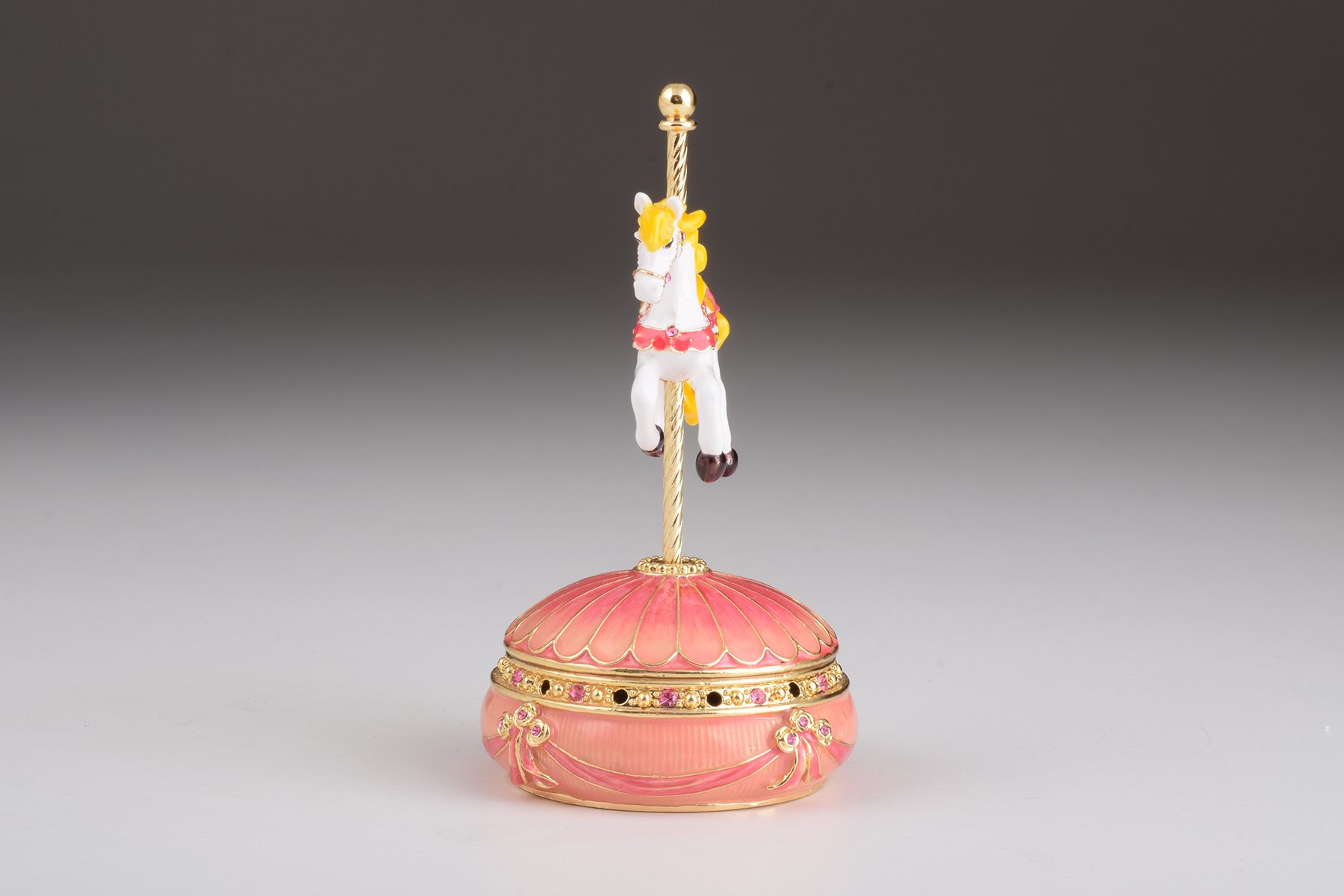 A beautifully crafted Pink Wind up Musical Carousel trinket box adorned with sparkling Austrian crystals and plated in 24K gold.