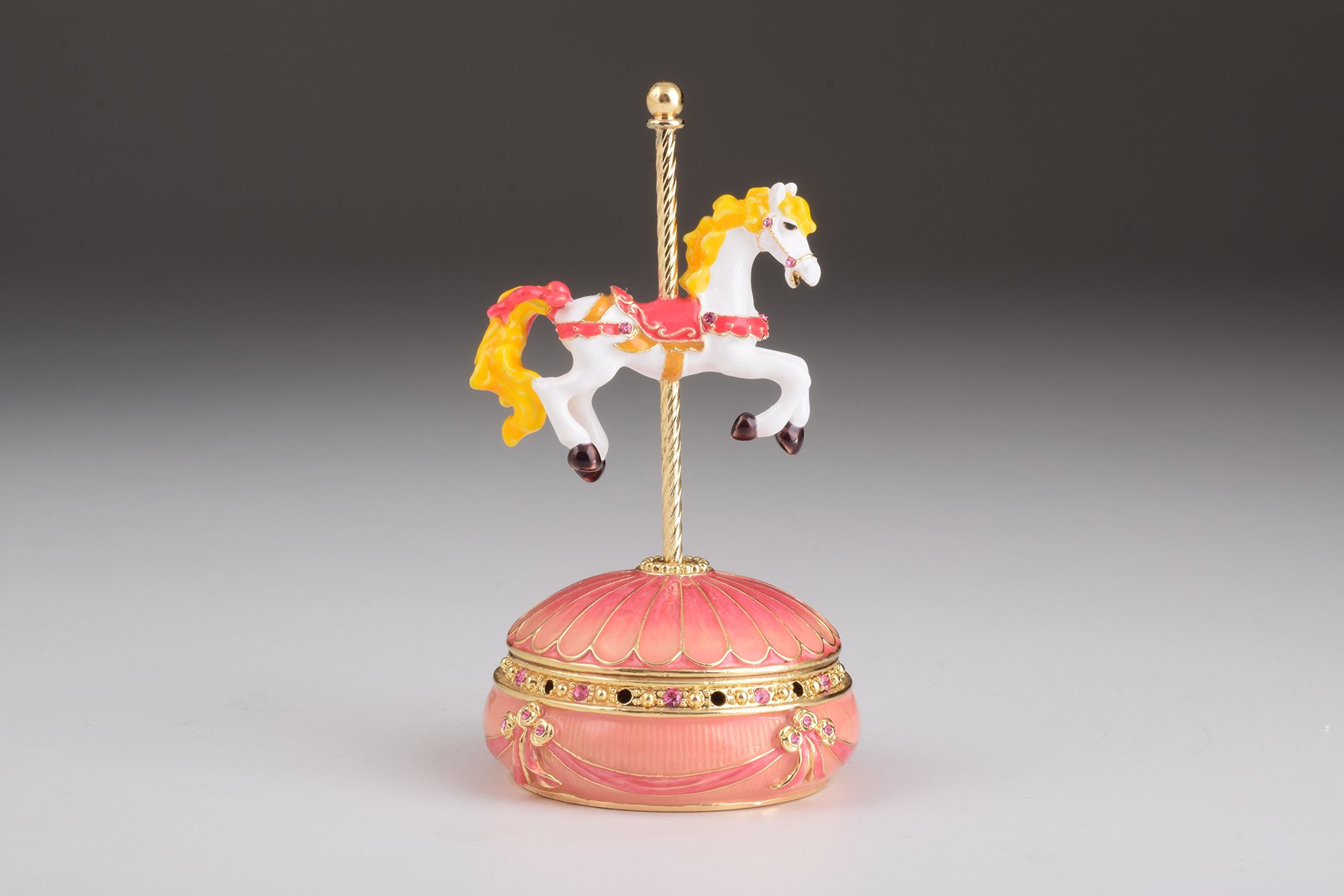 A beautifully crafted Pink Wind up Musical Carousel trinket box adorned with sparkling Austrian crystals and plated in 24K gold.