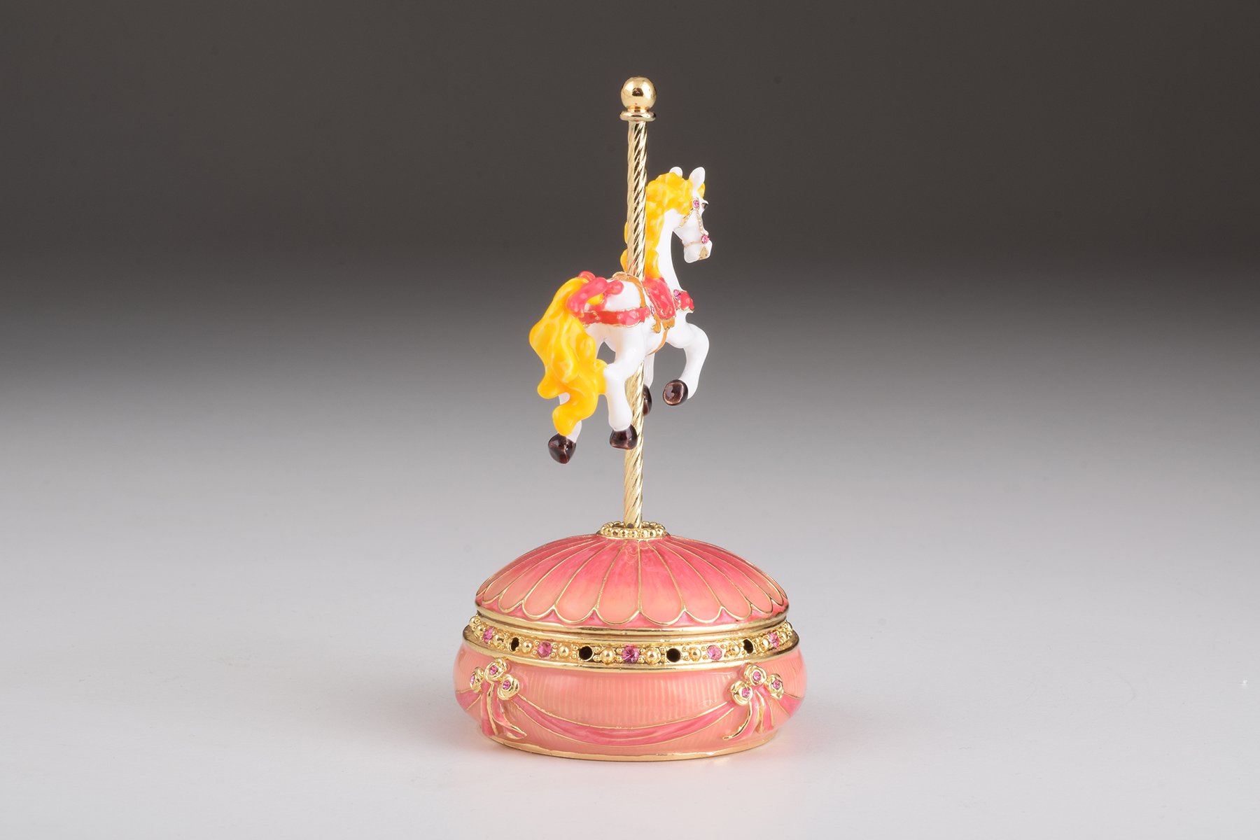 A beautifully crafted Pink Wind up Musical Carousel trinket box adorned with sparkling Austrian crystals and plated in 24K gold.