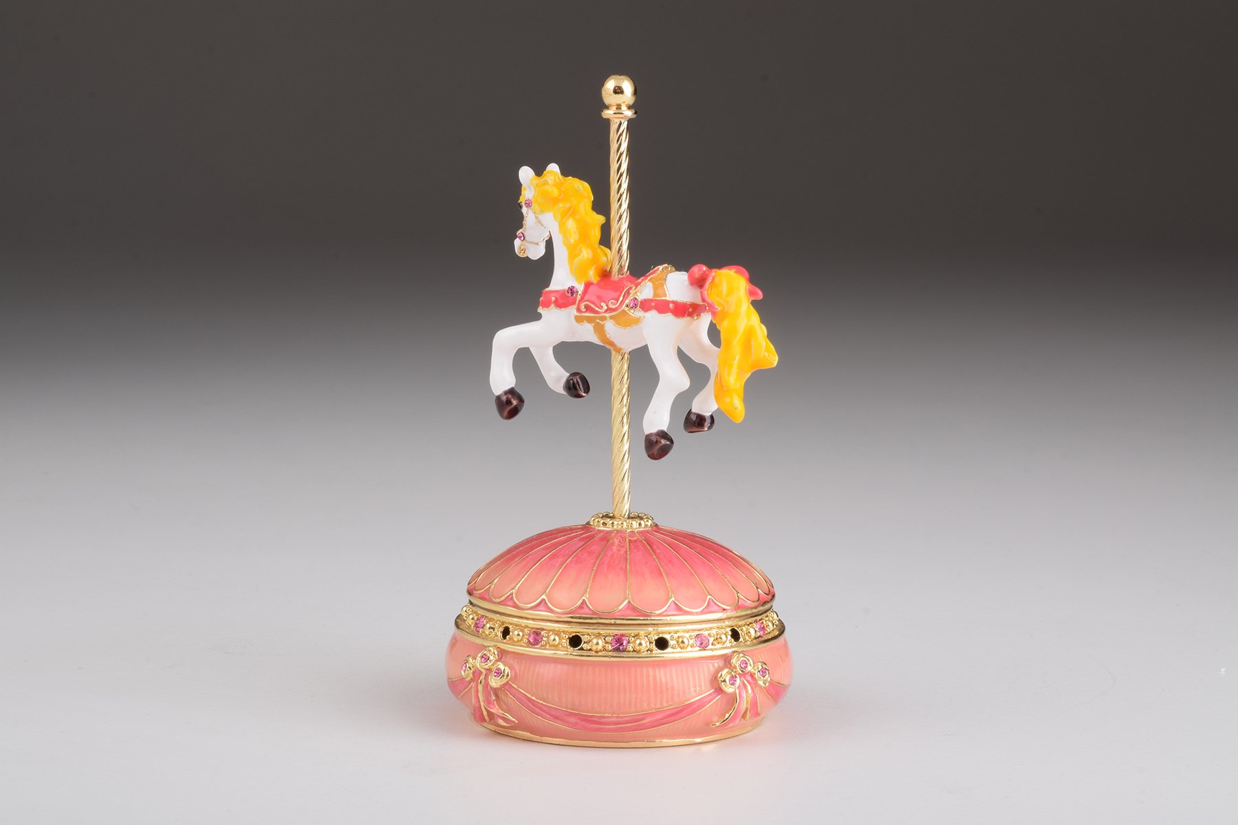 A beautifully crafted Pink Wind up Musical Carousel trinket box adorned with sparkling Austrian crystals and plated in 24K gold.