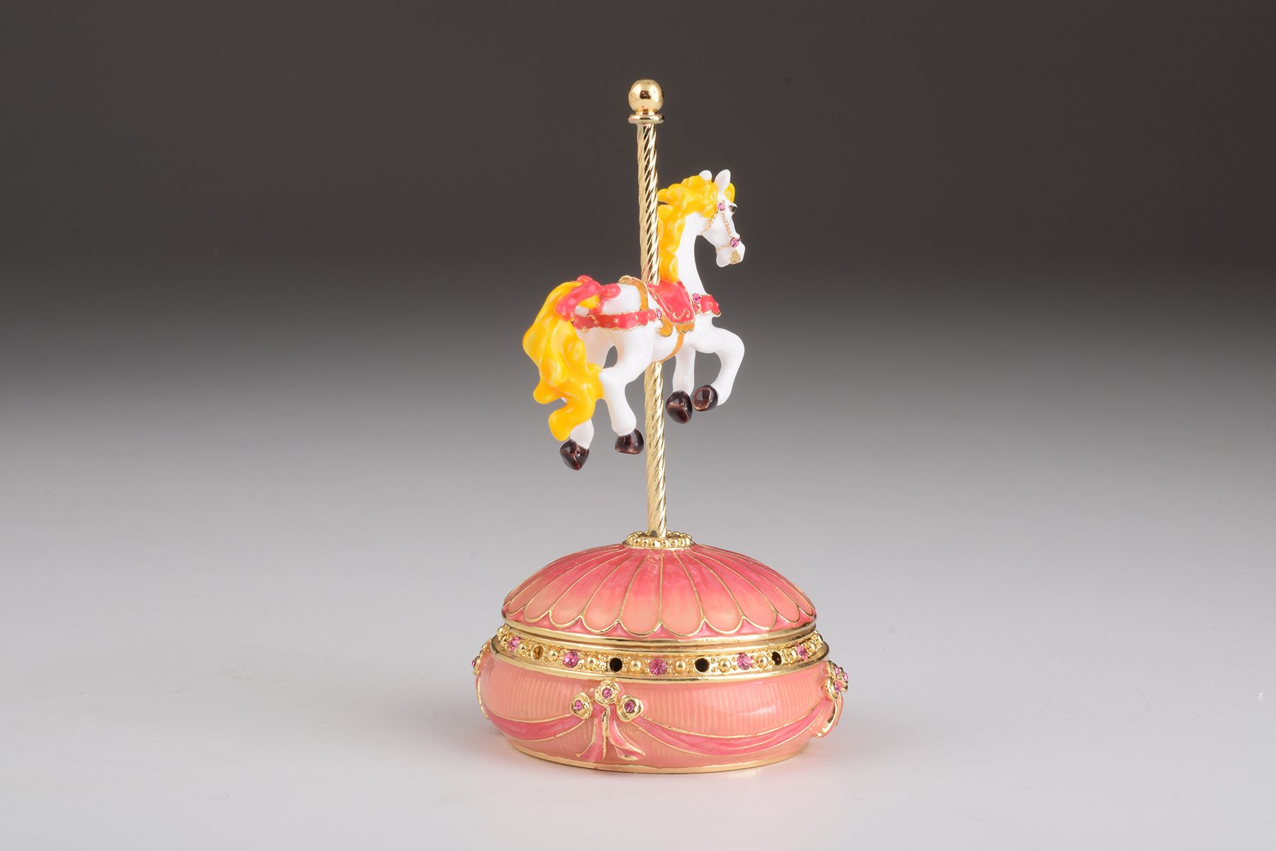 A beautifully crafted Pink Wind up Musical Carousel trinket box adorned with sparkling Austrian crystals and plated in 24K gold.