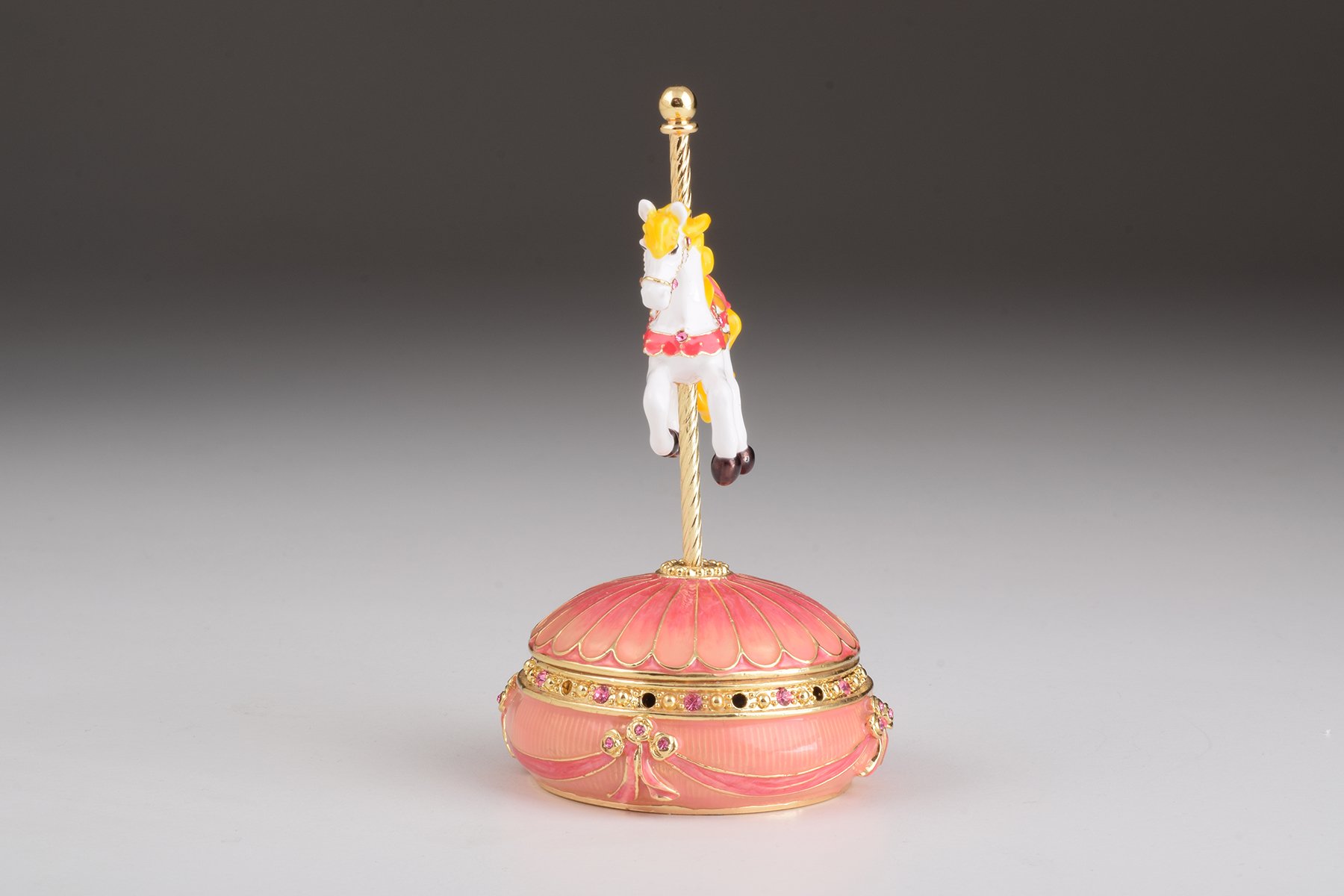 A beautifully crafted Pink Wind up Musical Carousel trinket box adorned with sparkling Austrian crystals and plated in 24K gold.