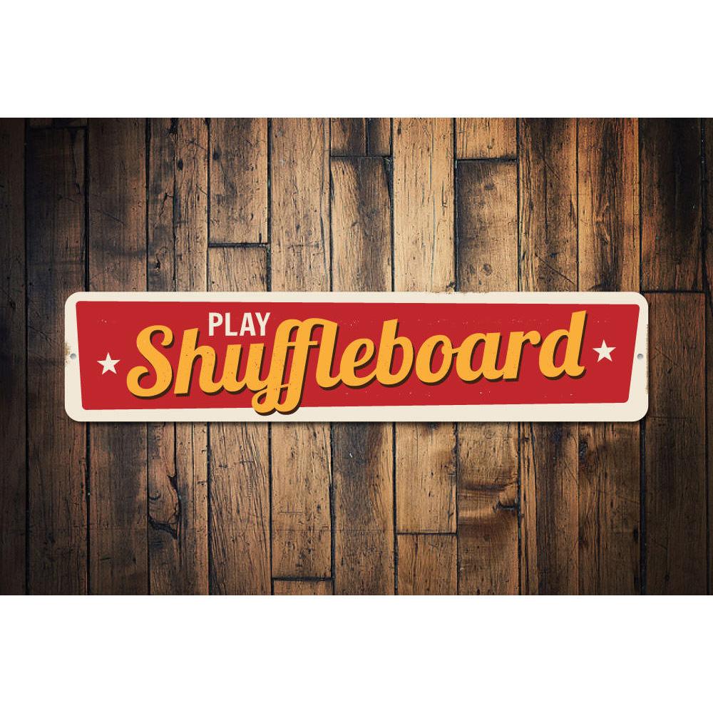 A decorative Play Shuffleboard Sign made of durable aluminum, featuring customizable text and pre-drilled holes for easy mounting.