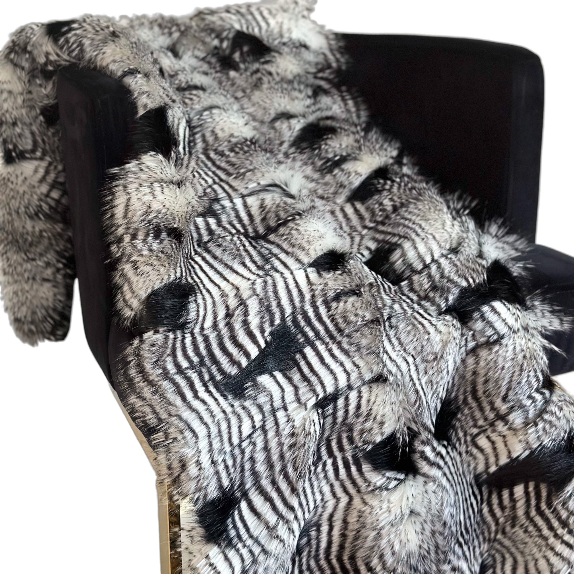 Plutus Black and White Feather Faux Fur Luxury Throw Blanket draped elegantly over a sofa, showcasing its plush texture and stylish design.