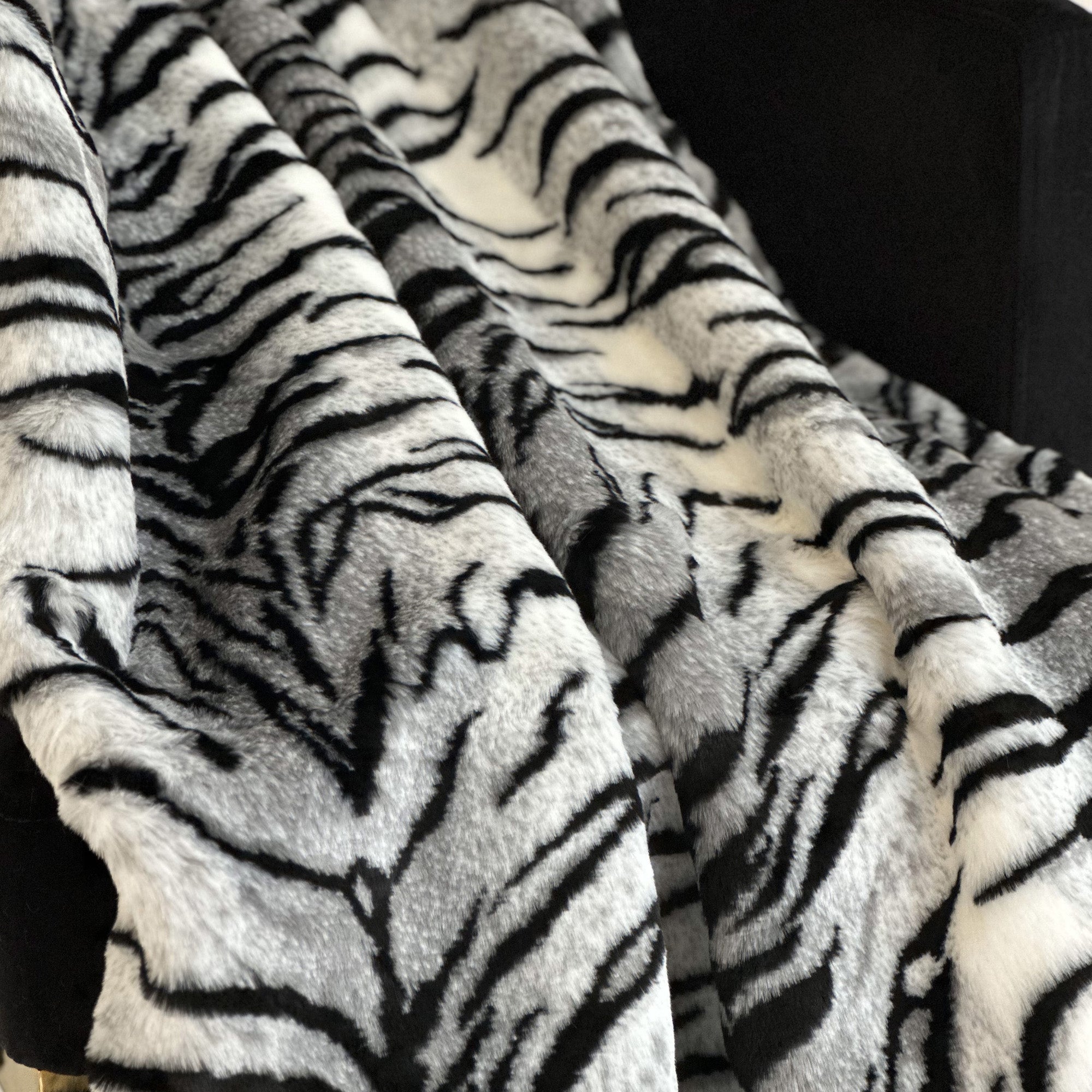 Plutus Black and White Zebra Faux Fur Luxury Throw Blanket draped elegantly over a sofa, showcasing its fluffy texture and stylish design.