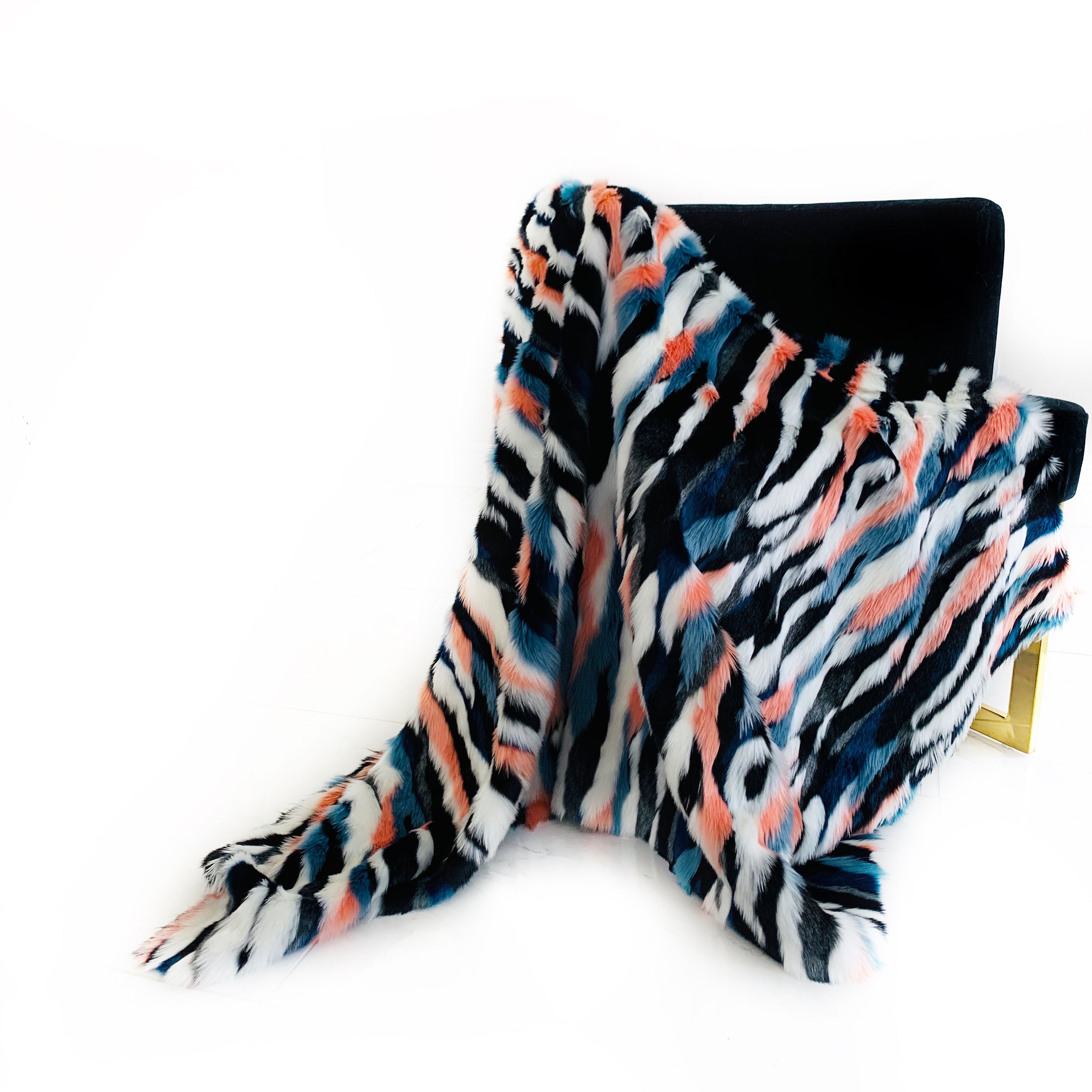 Plutus Black, Blue, Pink Unicorn Faux Fur Luxury Throw Blanket draped elegantly over a sofa, showcasing its plush texture and vibrant colors.