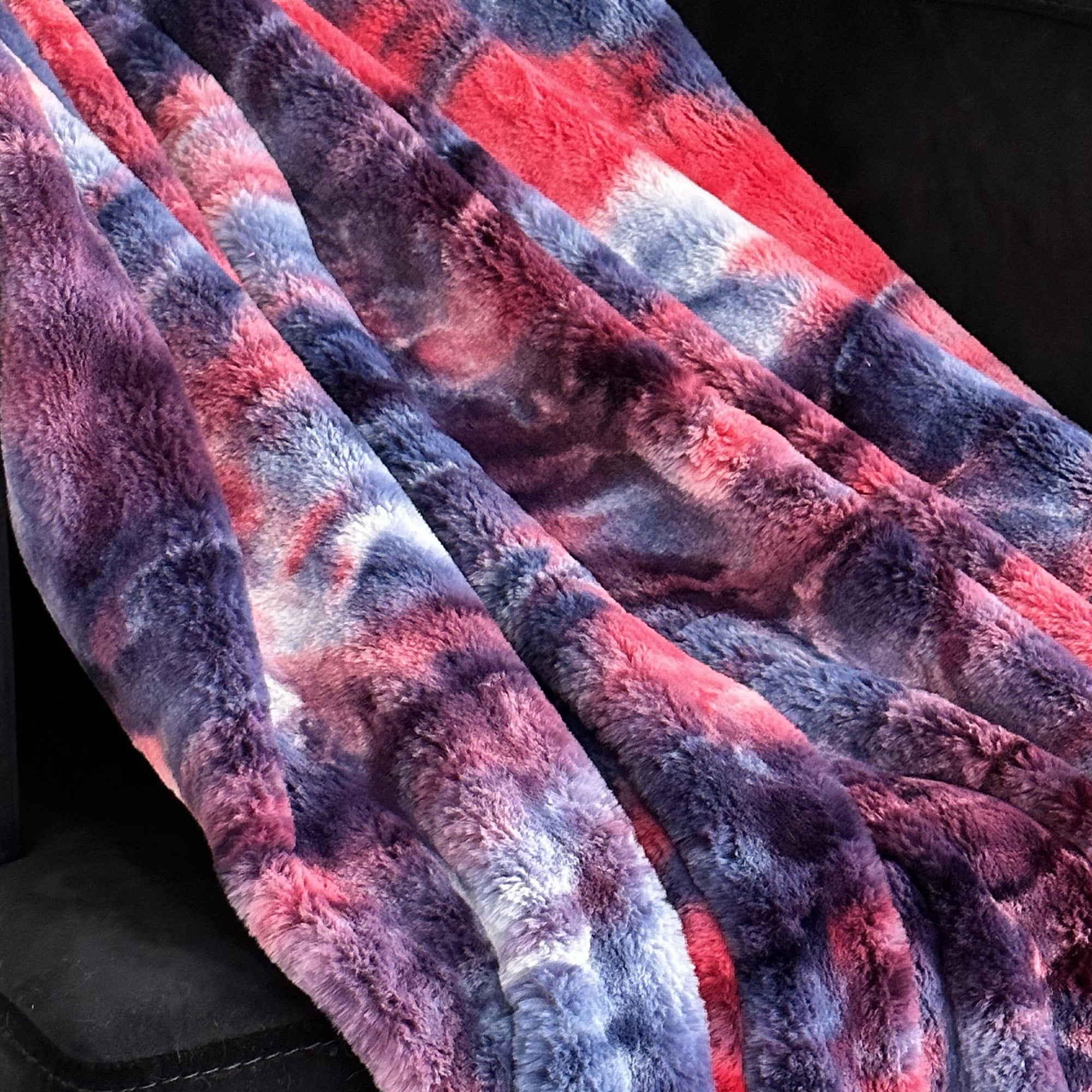 Plutus Blue Red White Faux Fur Luxury Throw Blanket draped elegantly over a sofa, showcasing its plush texture and vibrant colors.