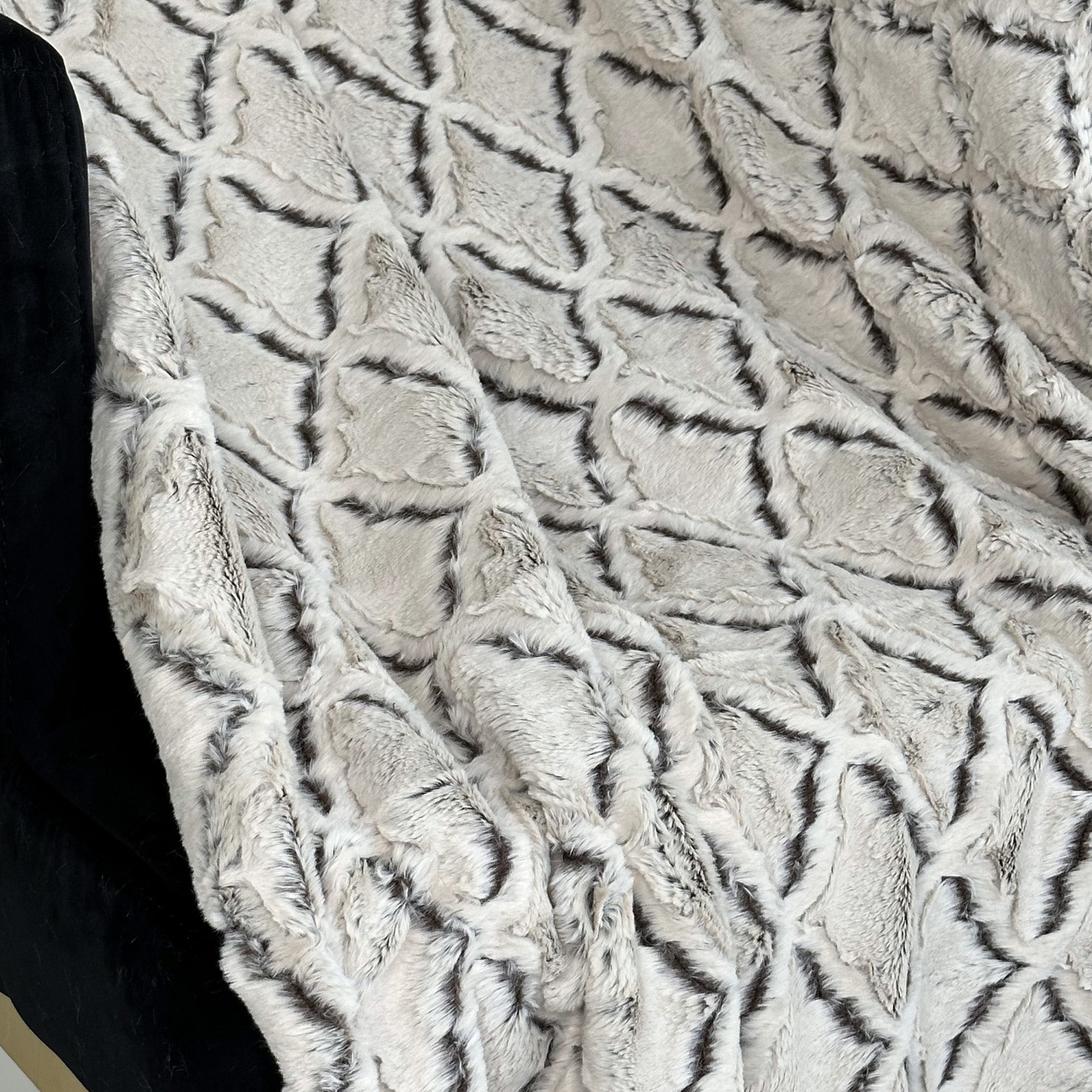 Plutus Brown Beige Diamond Faux Fur Luxury Throw Blanket draped elegantly on a couch, showcasing its soft texture and reversible design.