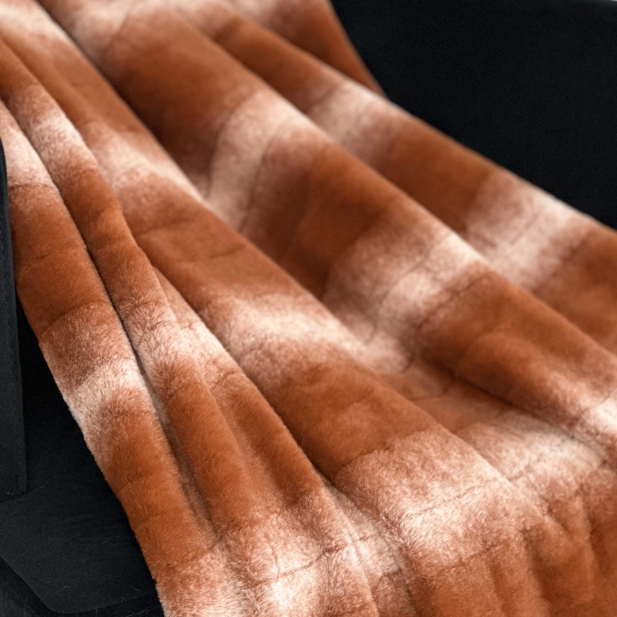 Plutus Orange Brown Faux Fur Luxury Throw Blanket draped elegantly over a couch, showcasing its rich color and soft texture.