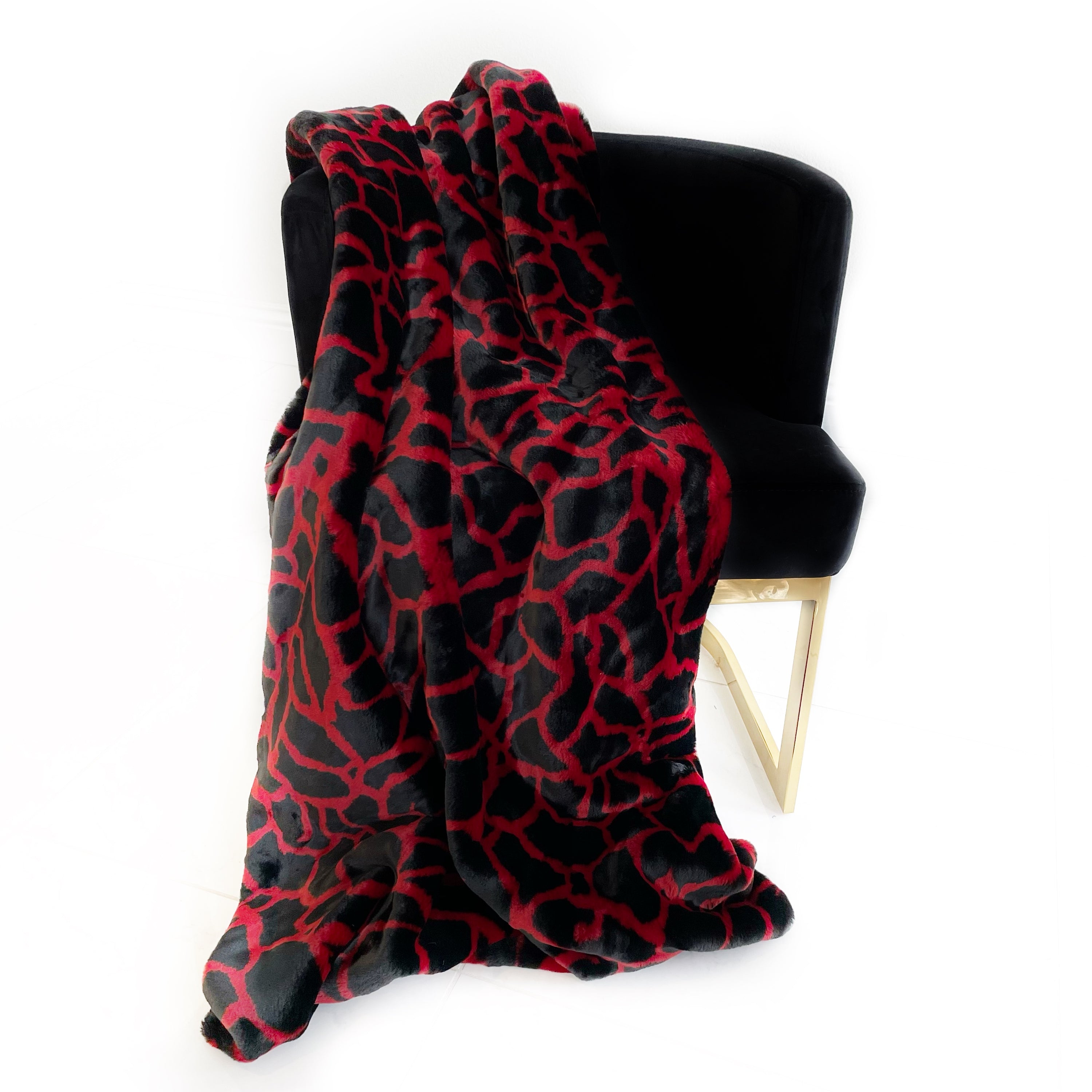 Plutus Red Black Plush Faux Fur Luxury Throw Blanket draped elegantly on a sofa, showcasing its rich colors and plush texture.