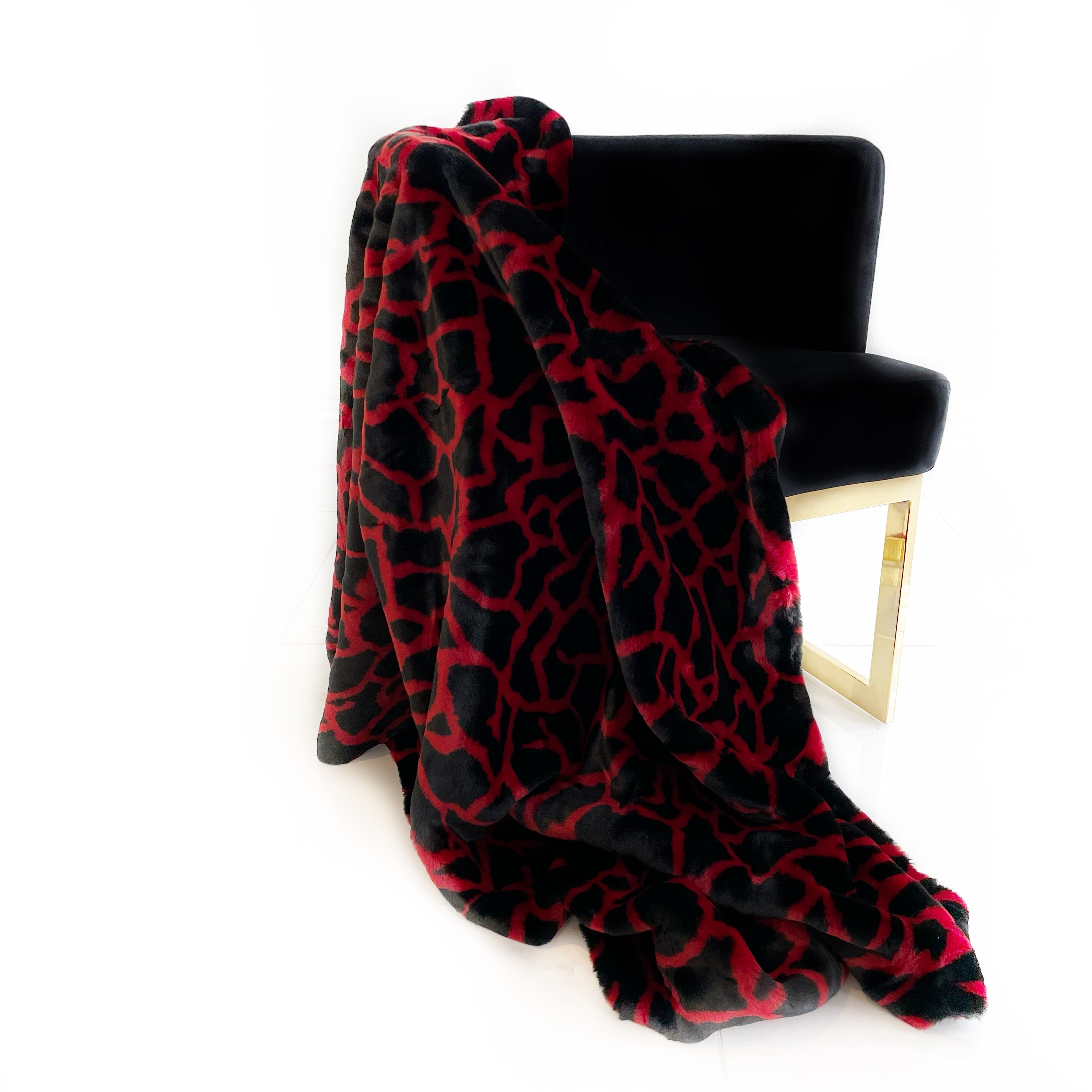 Plutus Red Black Plush Faux Fur Luxury Throw Blanket draped elegantly on a sofa, showcasing its rich colors and plush texture.