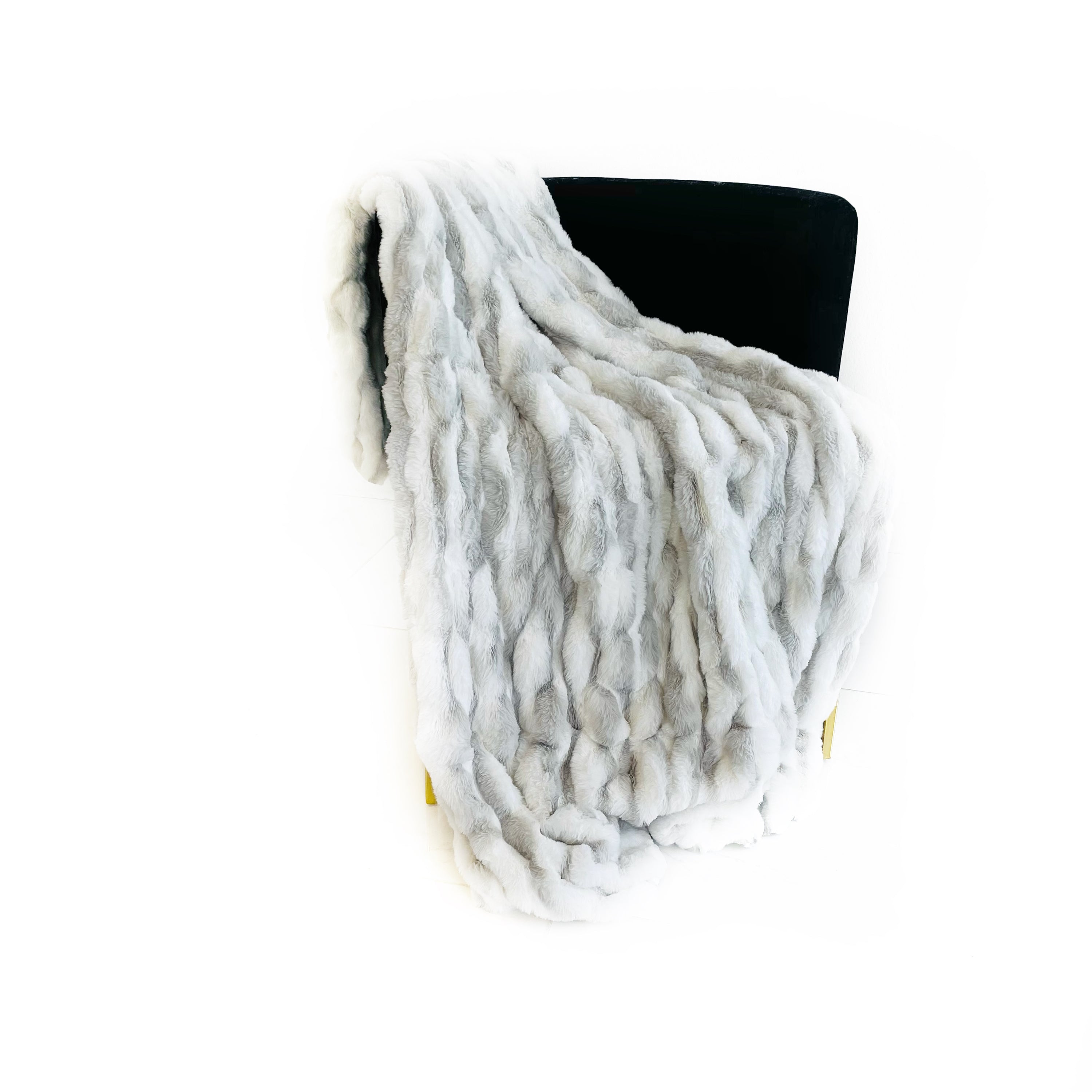 Plutus White Silver Snow Chinchilla Faux Fur Luxury Throw Blanket draped elegantly on a sofa, showcasing its plush texture and reversible design.