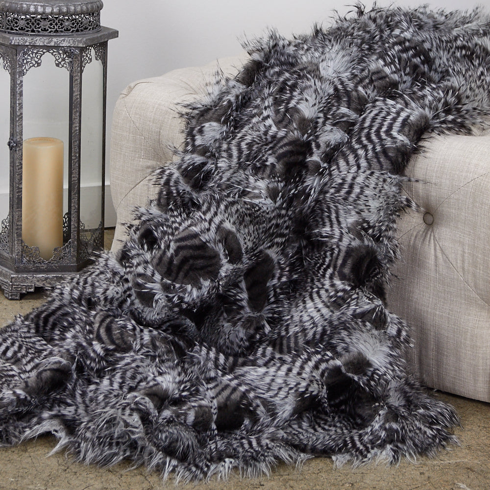 Porcupine Grey and Silver Faux Fur Luxury Throw draped elegantly over a couch, showcasing its plush texture and stylish colors.