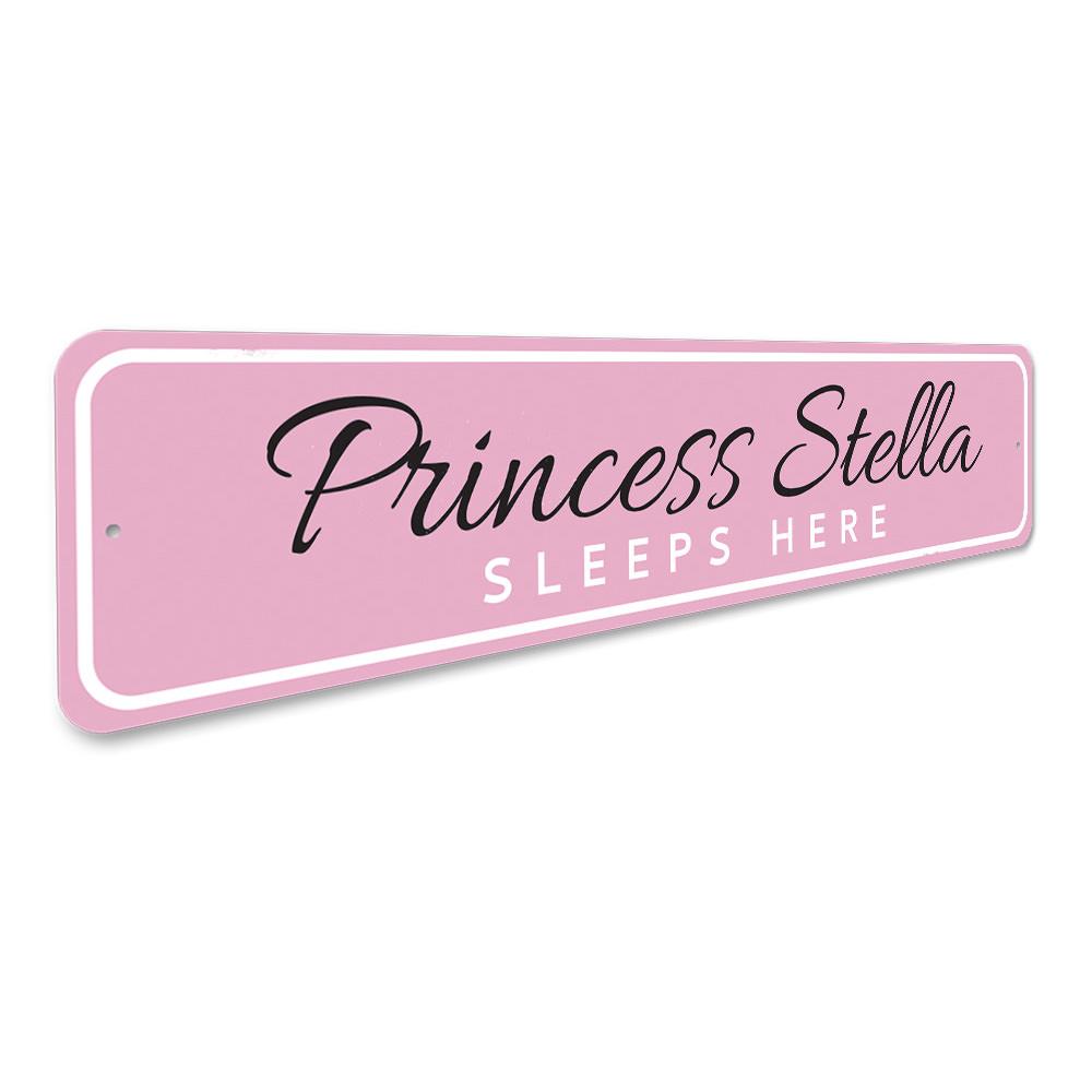 A decorative metal sign reading 'Princess Sleeps Here', featuring a charming design suitable for a child's room.