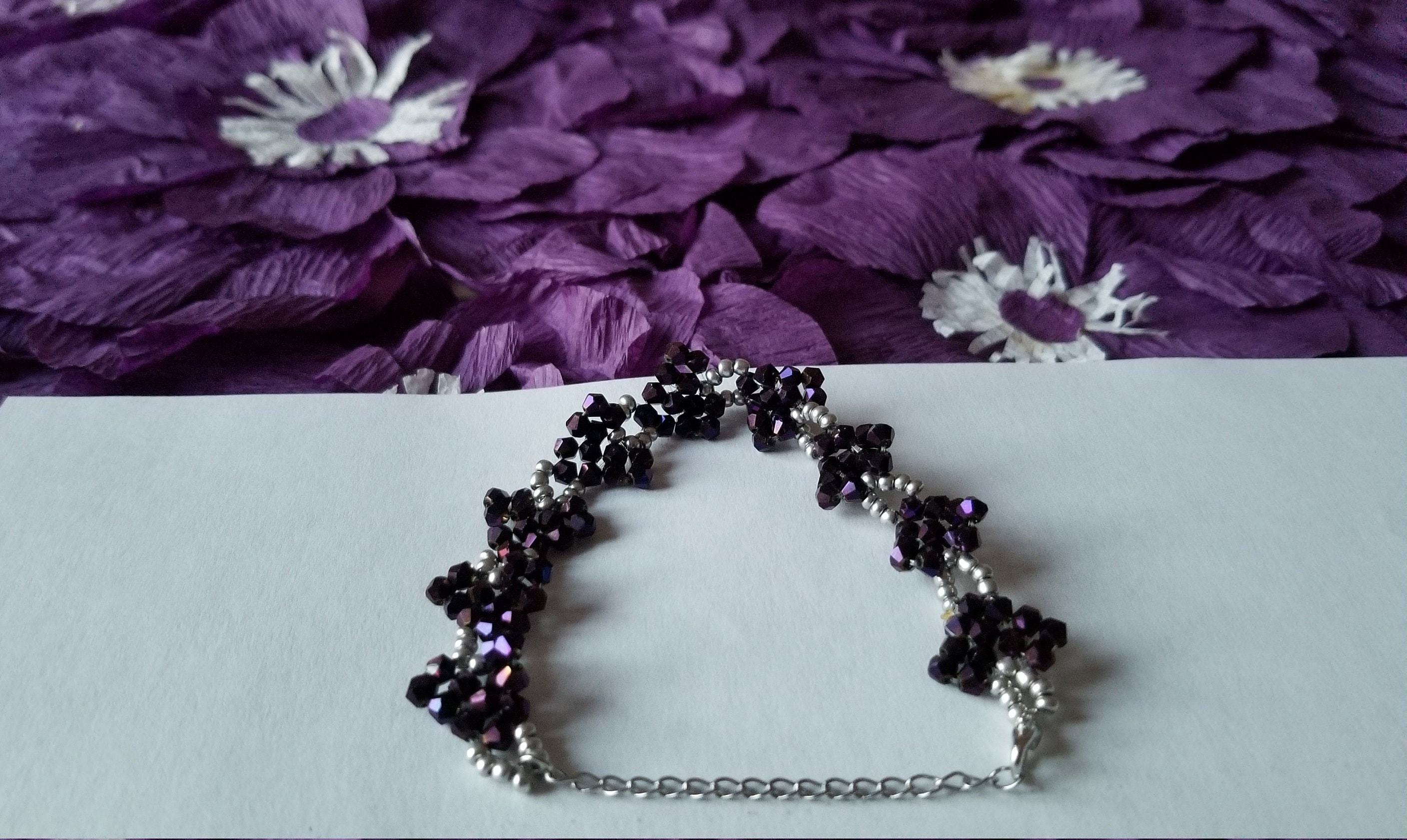 A stylish purple beaded bracelet featuring sparkly purple and silver beads arranged in a heart-shaped pattern on a stainless steel chain.