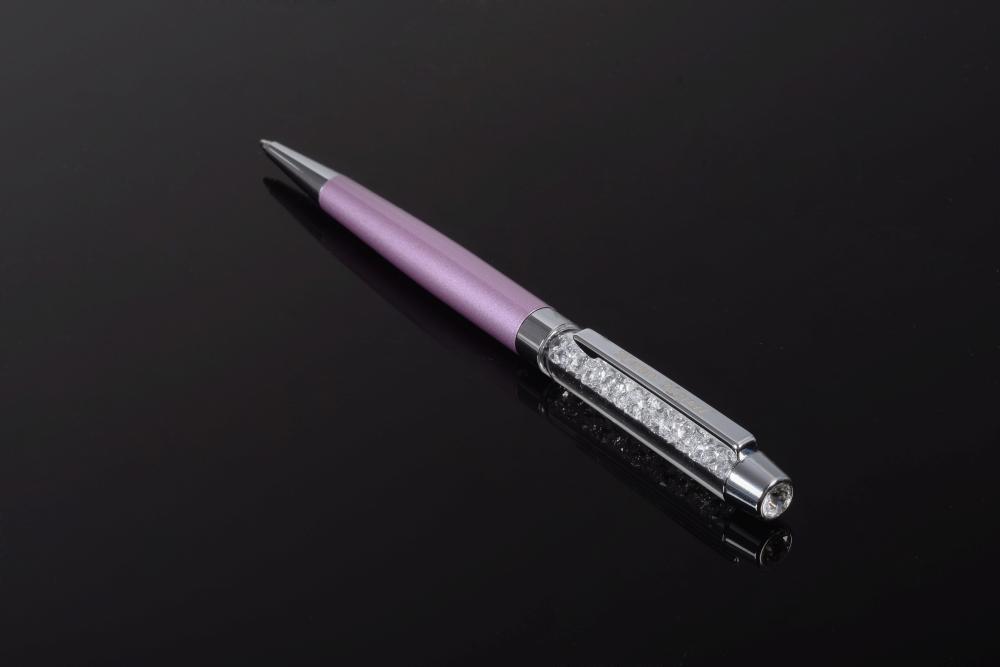 A luxurious purple pen adorned with sparkling Swarovski crystals, elegantly displayed in a black gift box.